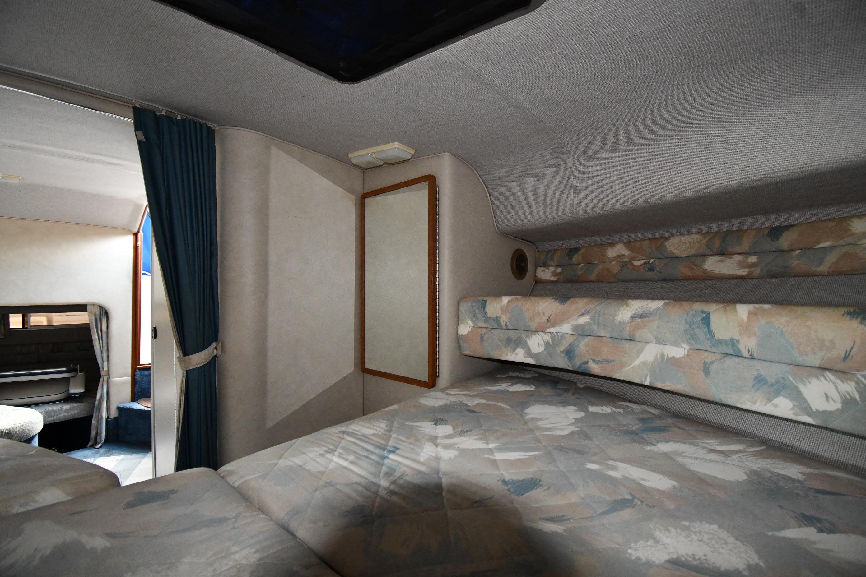 Interior cabin of 1993 Sea Ray 300 Sundancer with cozy sleeping area and patterned upholstery.