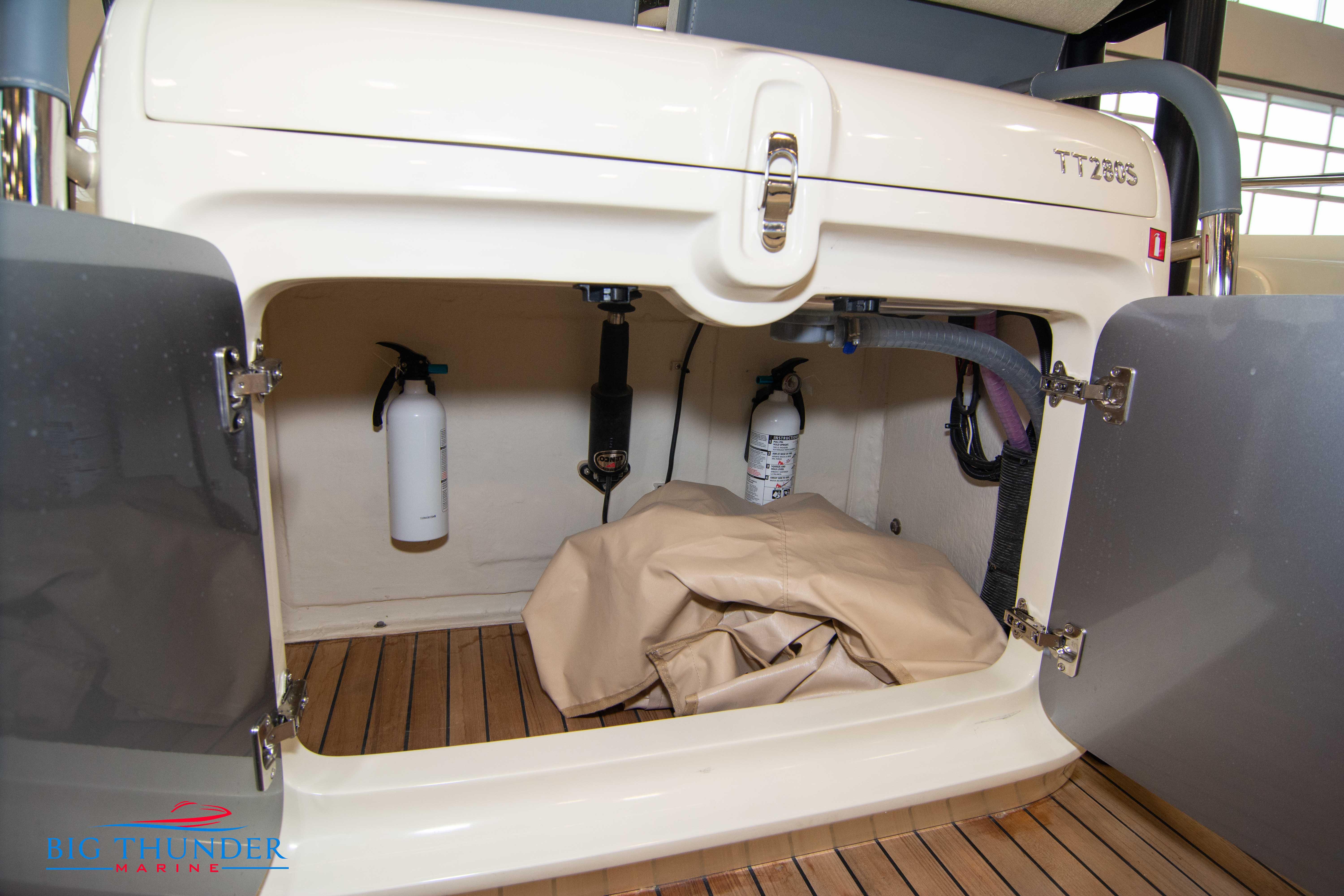 Storage compartment of 2024 Invictus TT280S boat with fire extinguishers and cover.