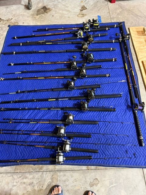 Several fishing rods and reels are laid out on a blue blanket on the floor.