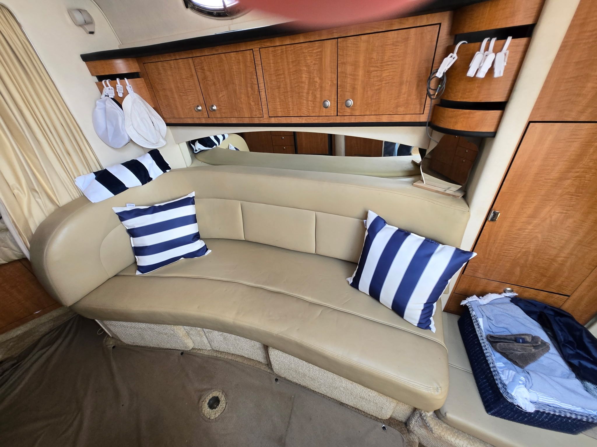 Interior of the Sea Ray 300 Sundancer with beige sofa and striped pillows.