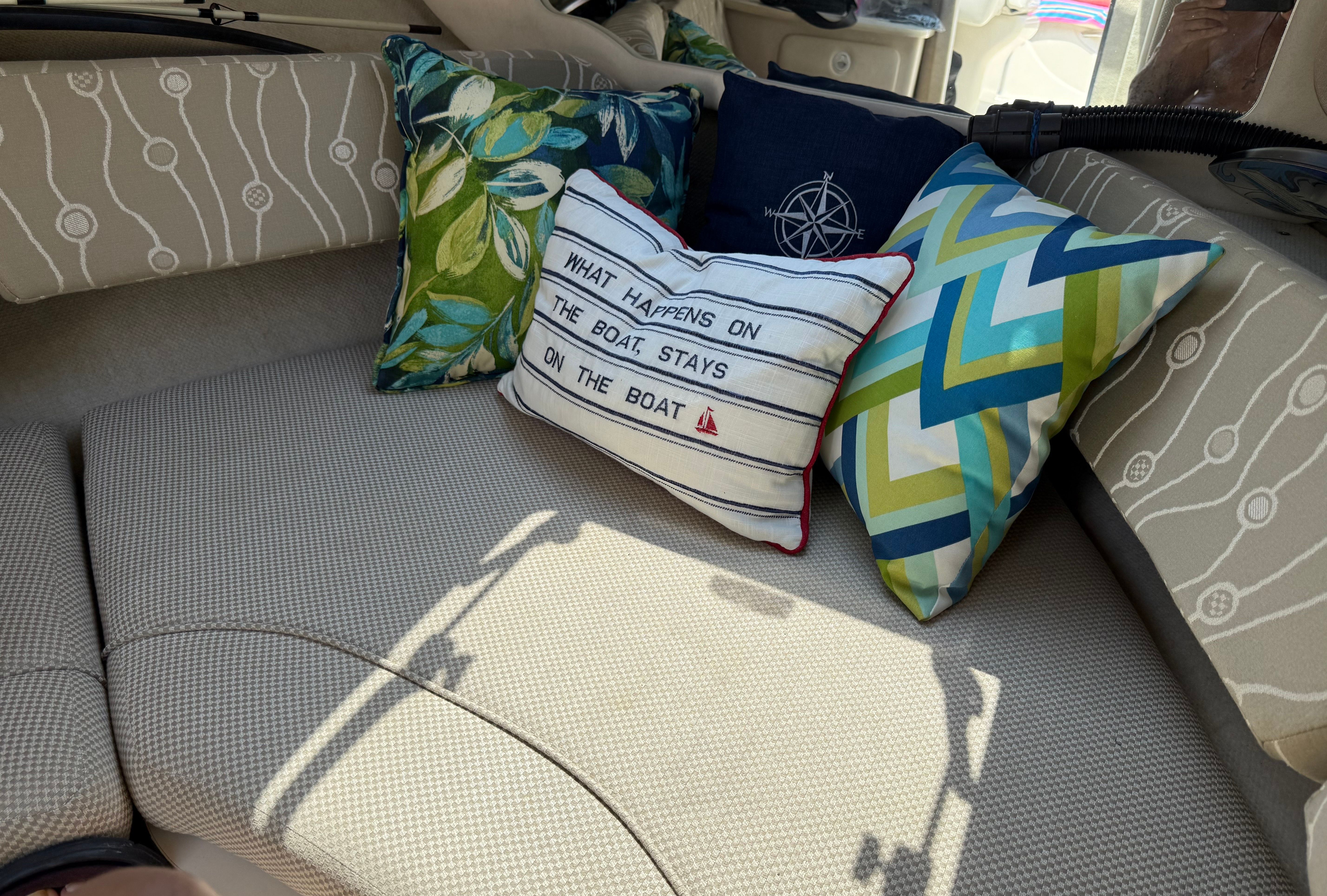 Interior of a Sea Ray 215 Weekender boat with decorative pillows.