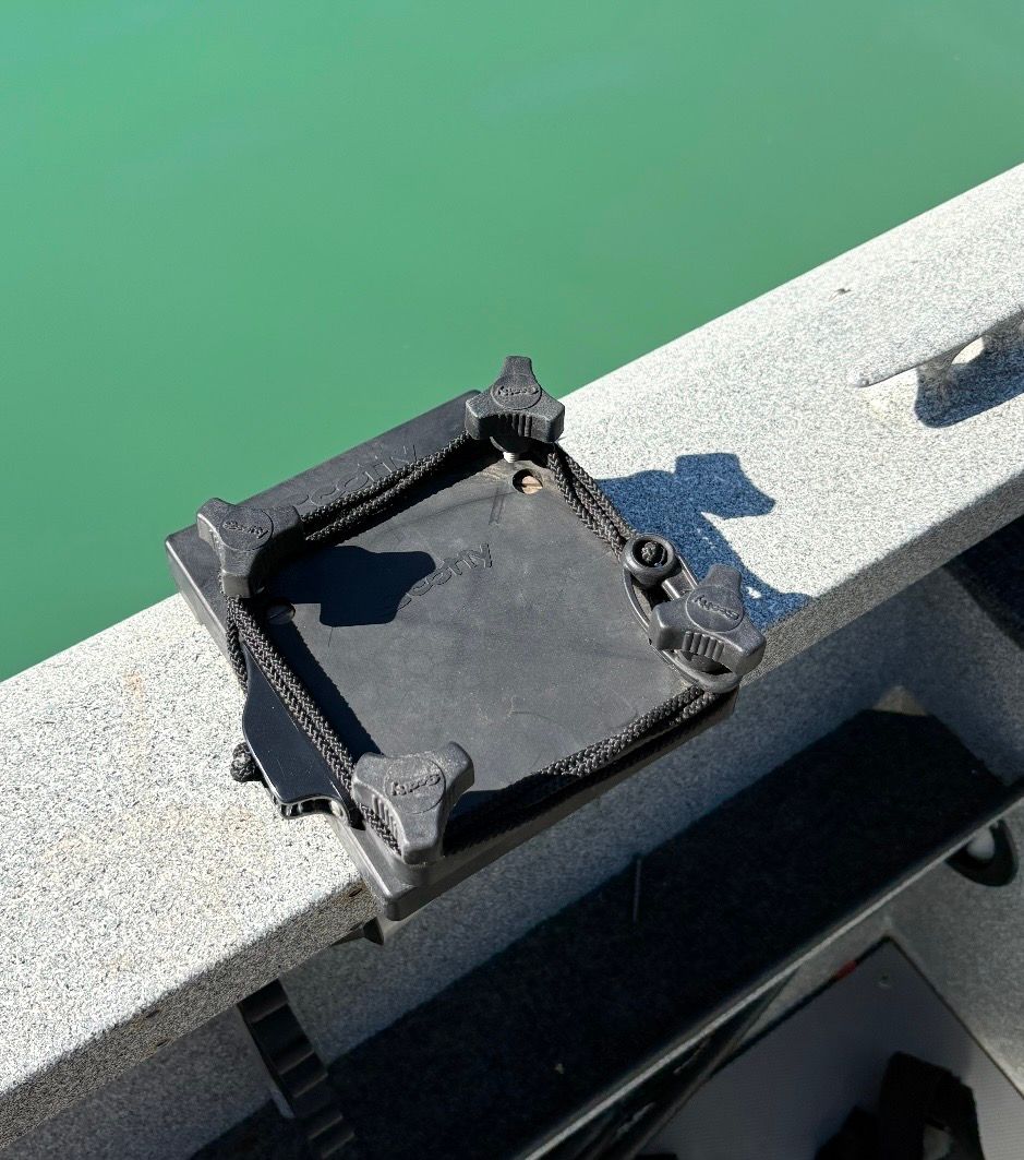 A black mount on a gray boat edge above green water.