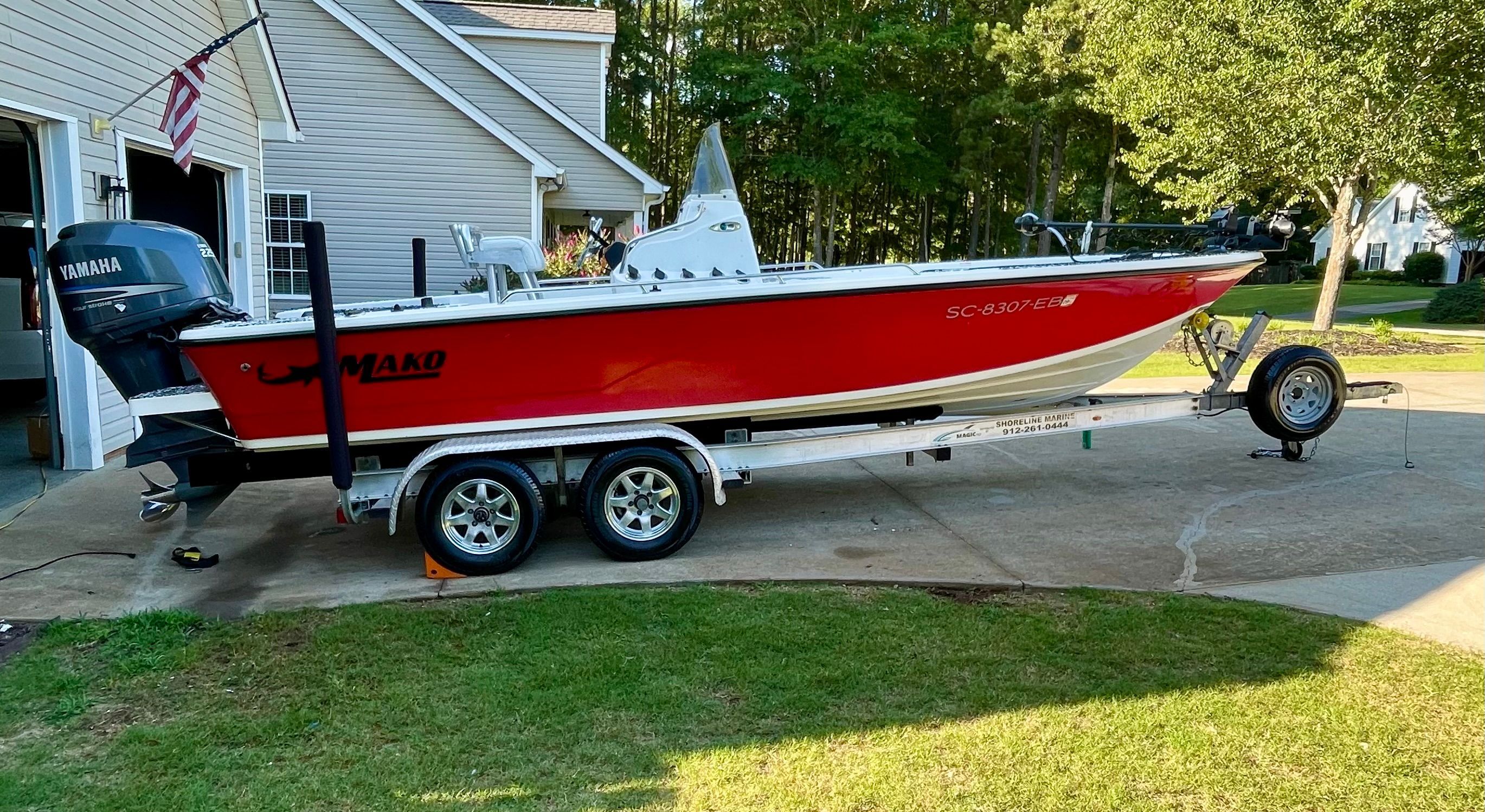 A red 2006 Mako 2101 Inshore boat on a trailer in a driveway.