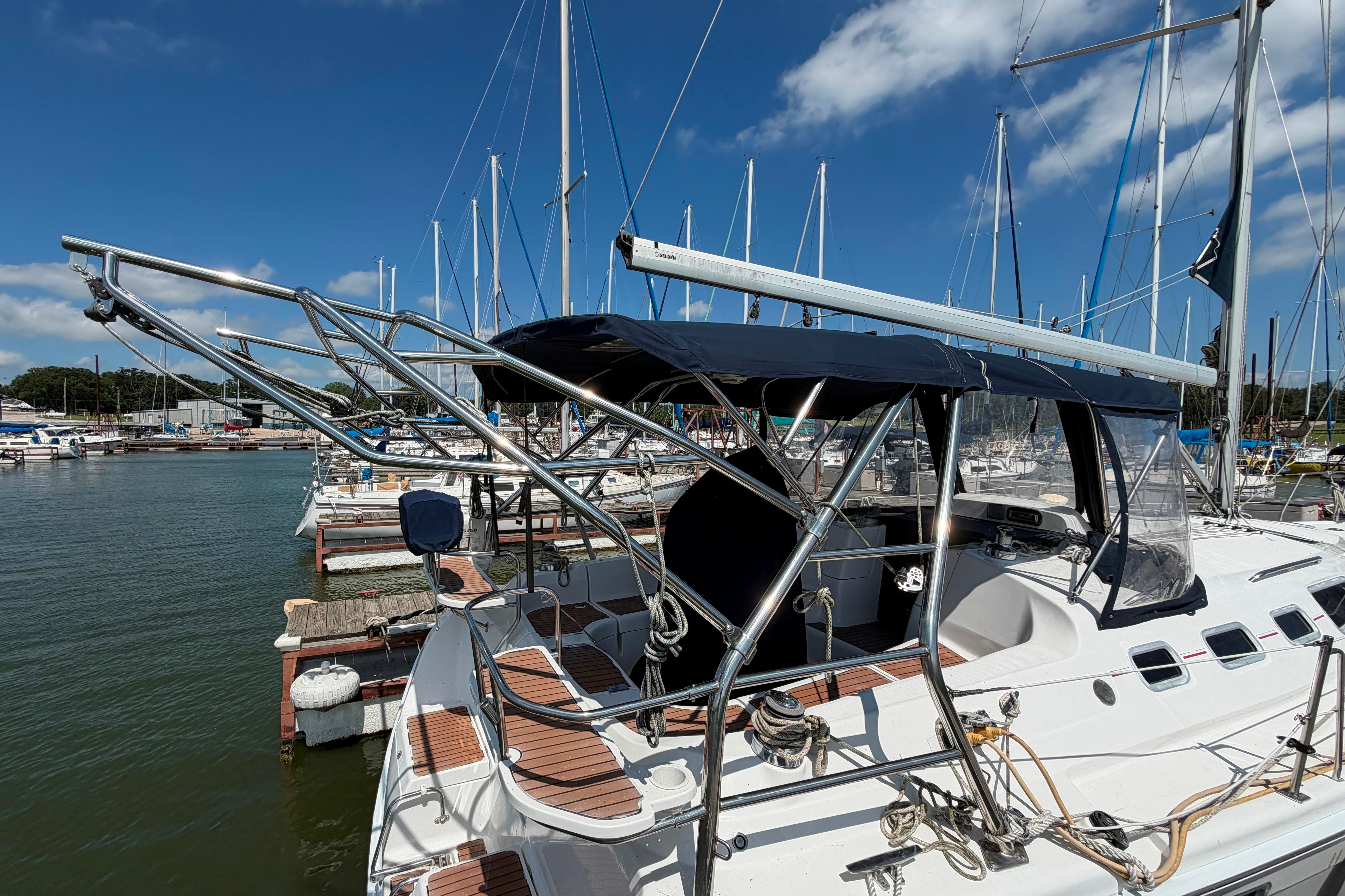 Sailboat docked at marina, Hunter 38 model, 2005, with blue canopy and stainless steel frame.