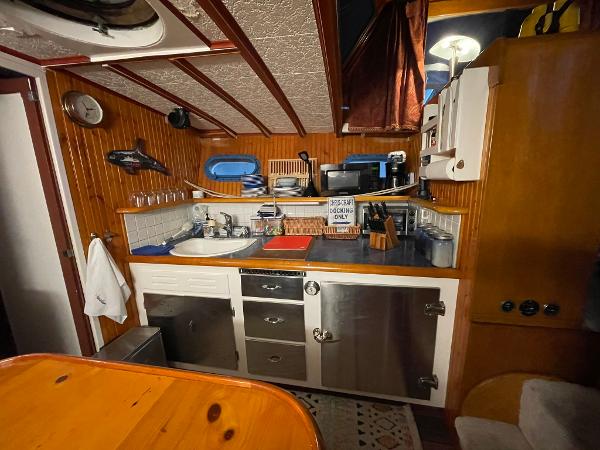 1951 Chris-Craft Catalina kitchen with wooden cabinetry, stainless steel appliances, and nautical decor.