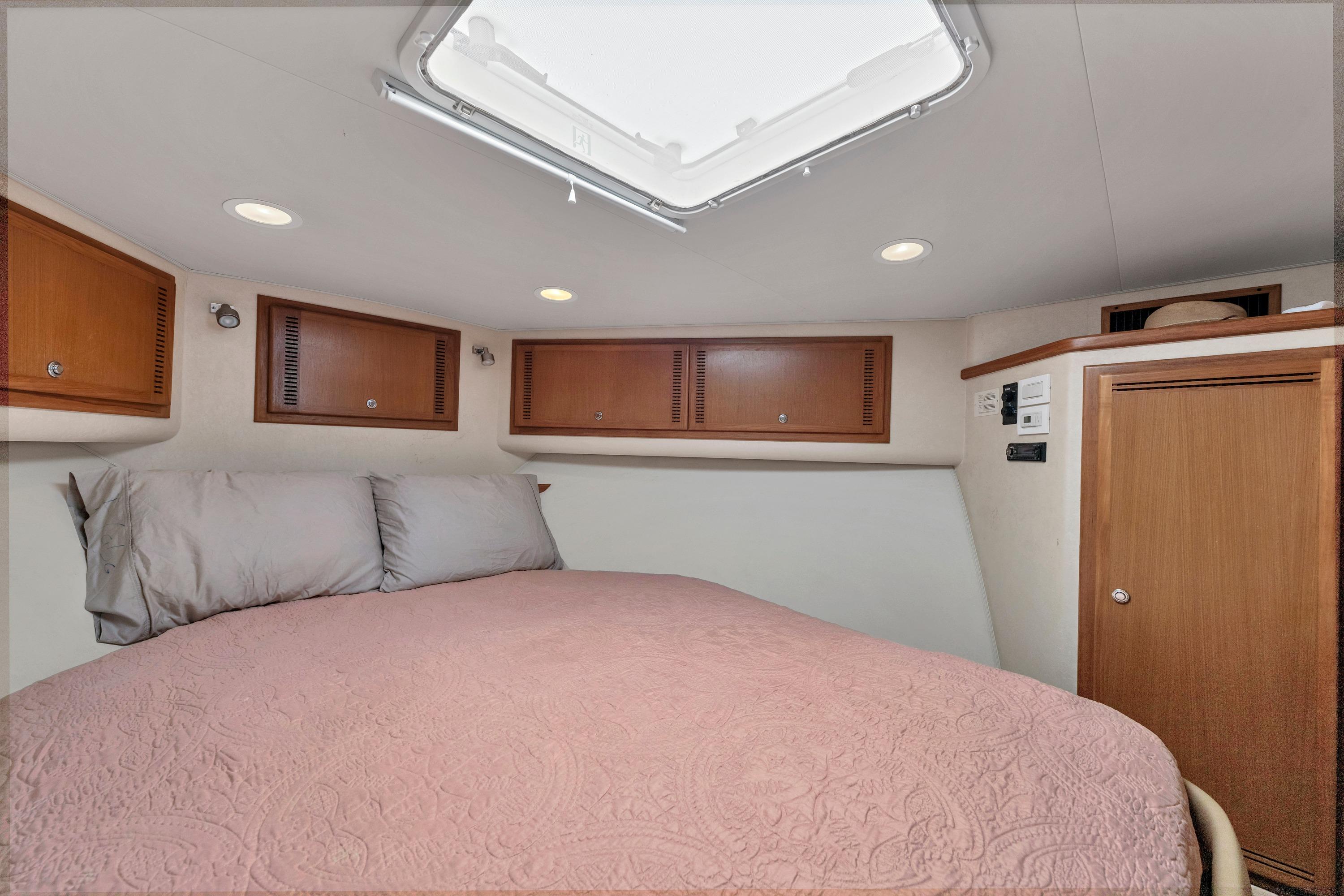 2010 Cabo 45 Express cabin interior with bed, wooden cabinets, and ceiling hatch.