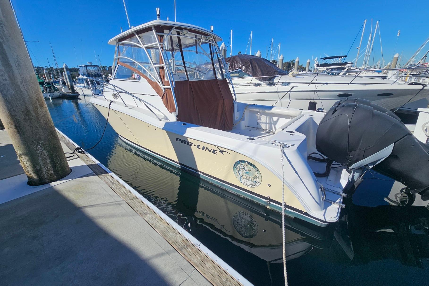 2006 Pro-Line 32 Express boat docked at marina under clear blue sky.