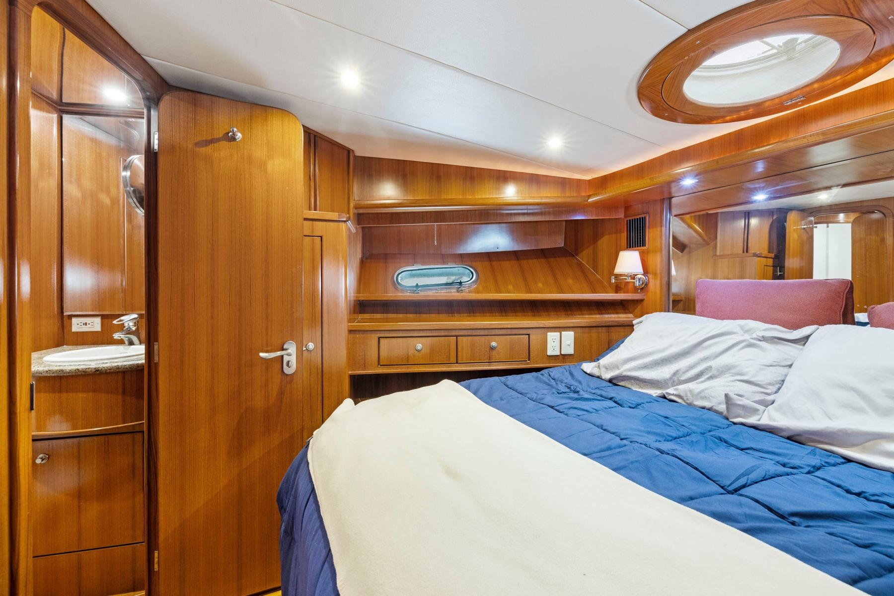 Luxurious 2002 Symbol 58 yacht cabin with wood paneling and cozy bedding.