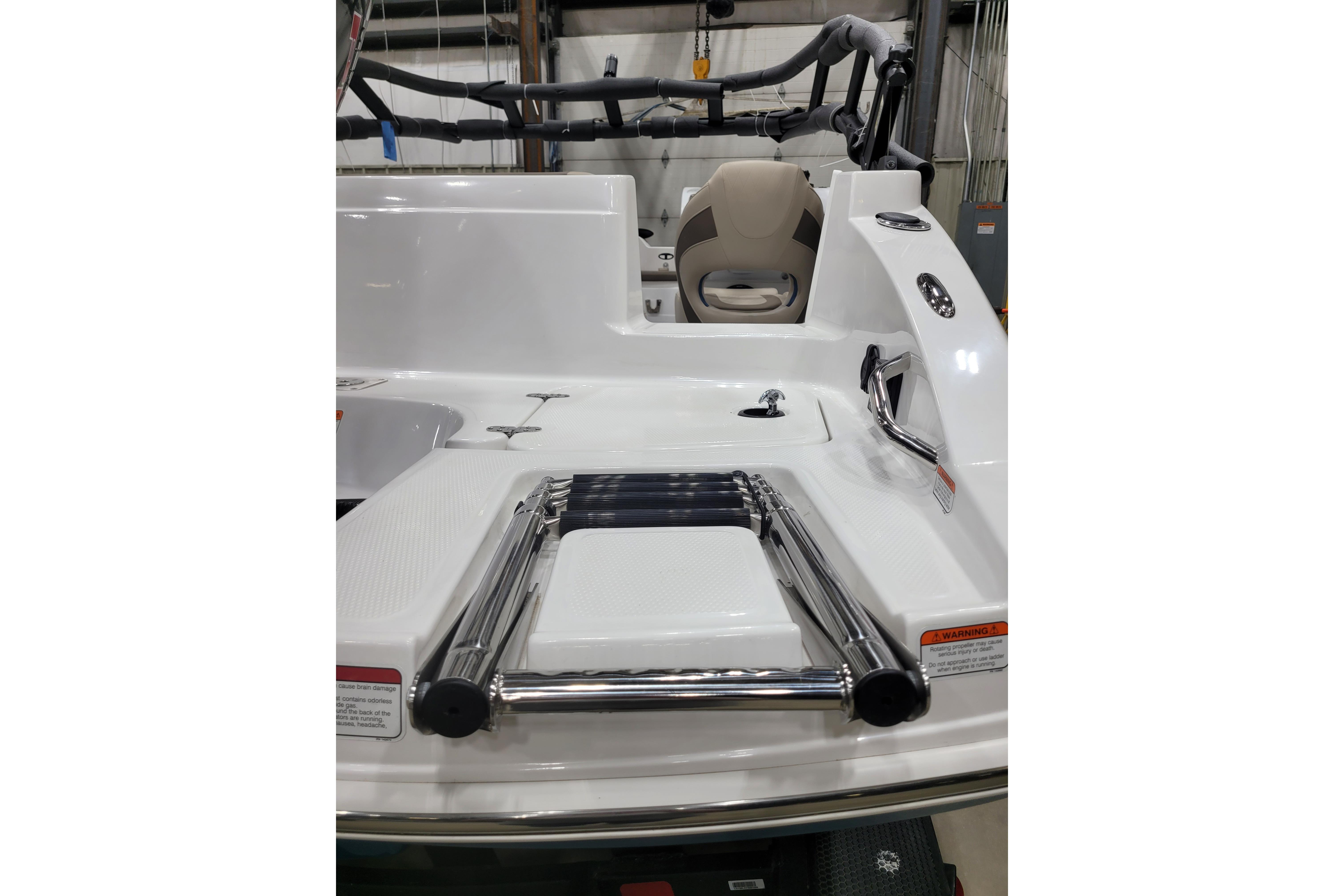 2026 Tahoe 2150 boat with swim platform and retractable ladder in a showroom.