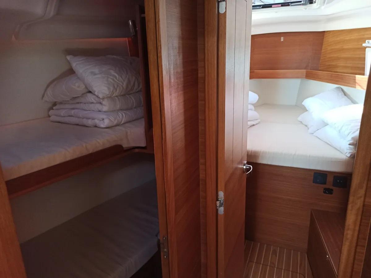 Cozy cabin interior of 2020 Elan Impression 45.1 yacht with wooden finish and bedding.