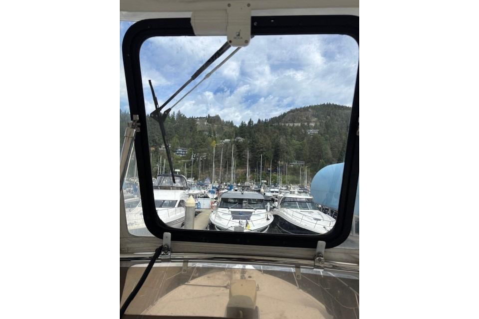 View from 2004 Canoe Cove Sedan, overlooking marina with boats and forested hills.