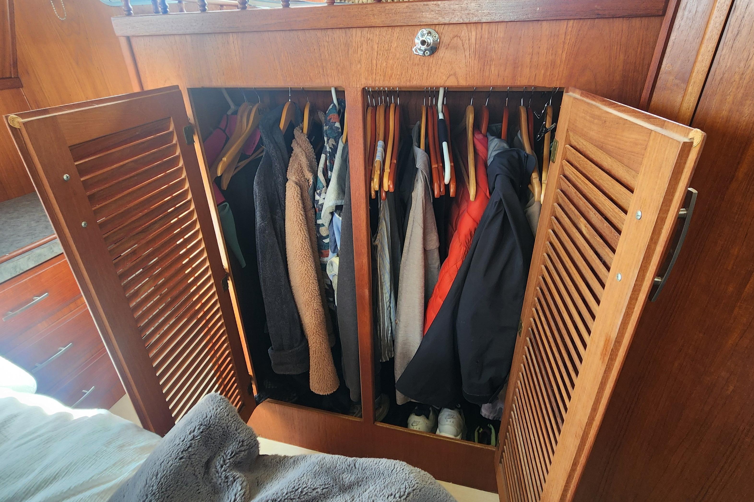 Wooden closet with clothes and shoes inside a 1981 Tollycraft 43 boat cabin.