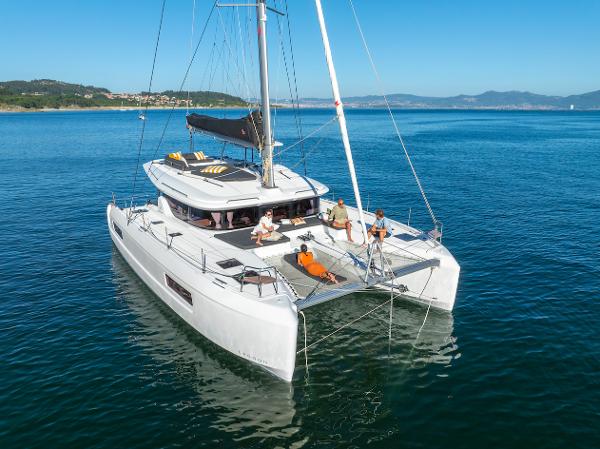 2025 Lagoon 43 catamaran sailing on calm blue waters with passengers relaxing on deck.