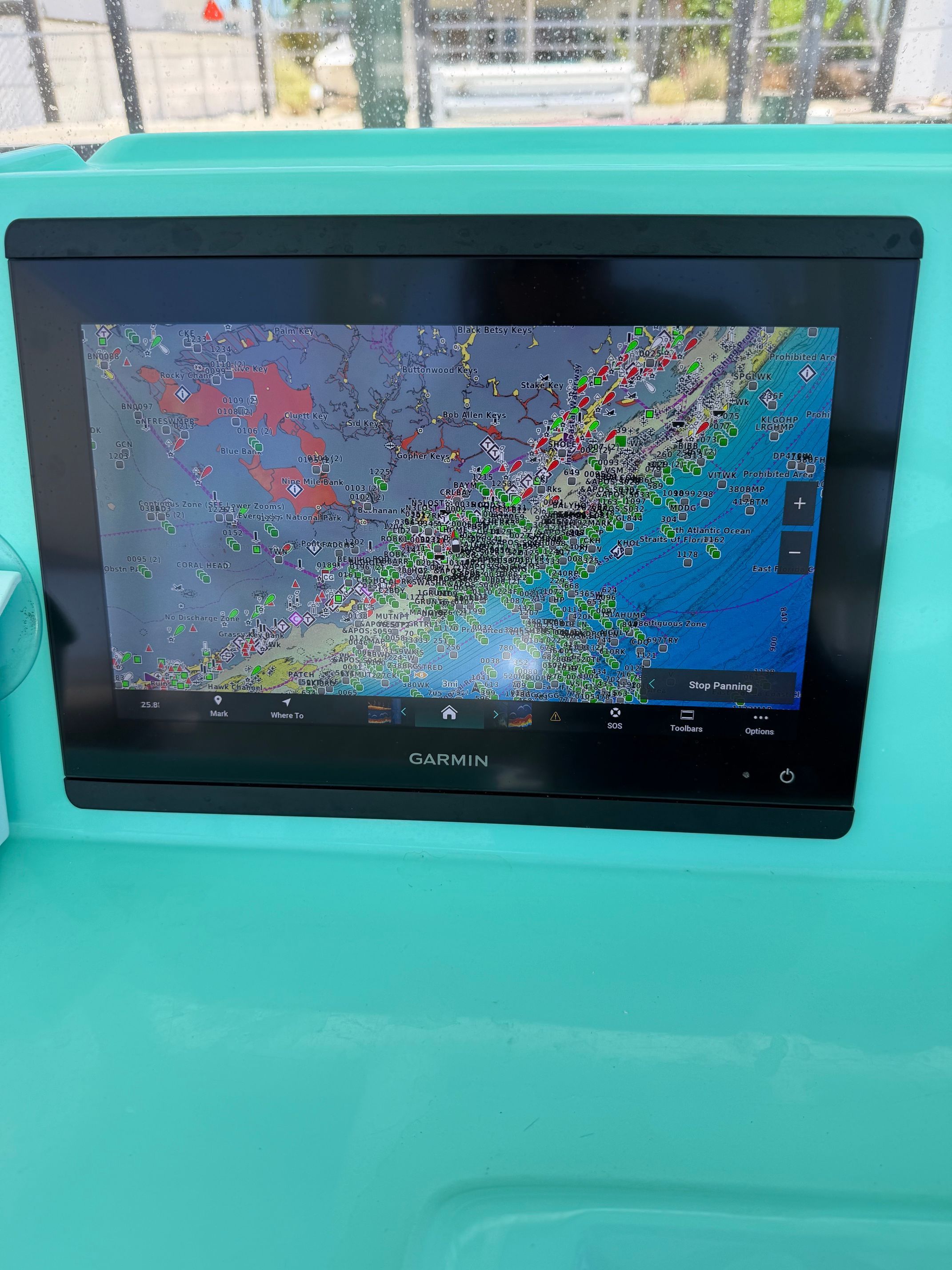 A Garmin navigation system on a turquoise boat panel displays a detailed nautical chart.