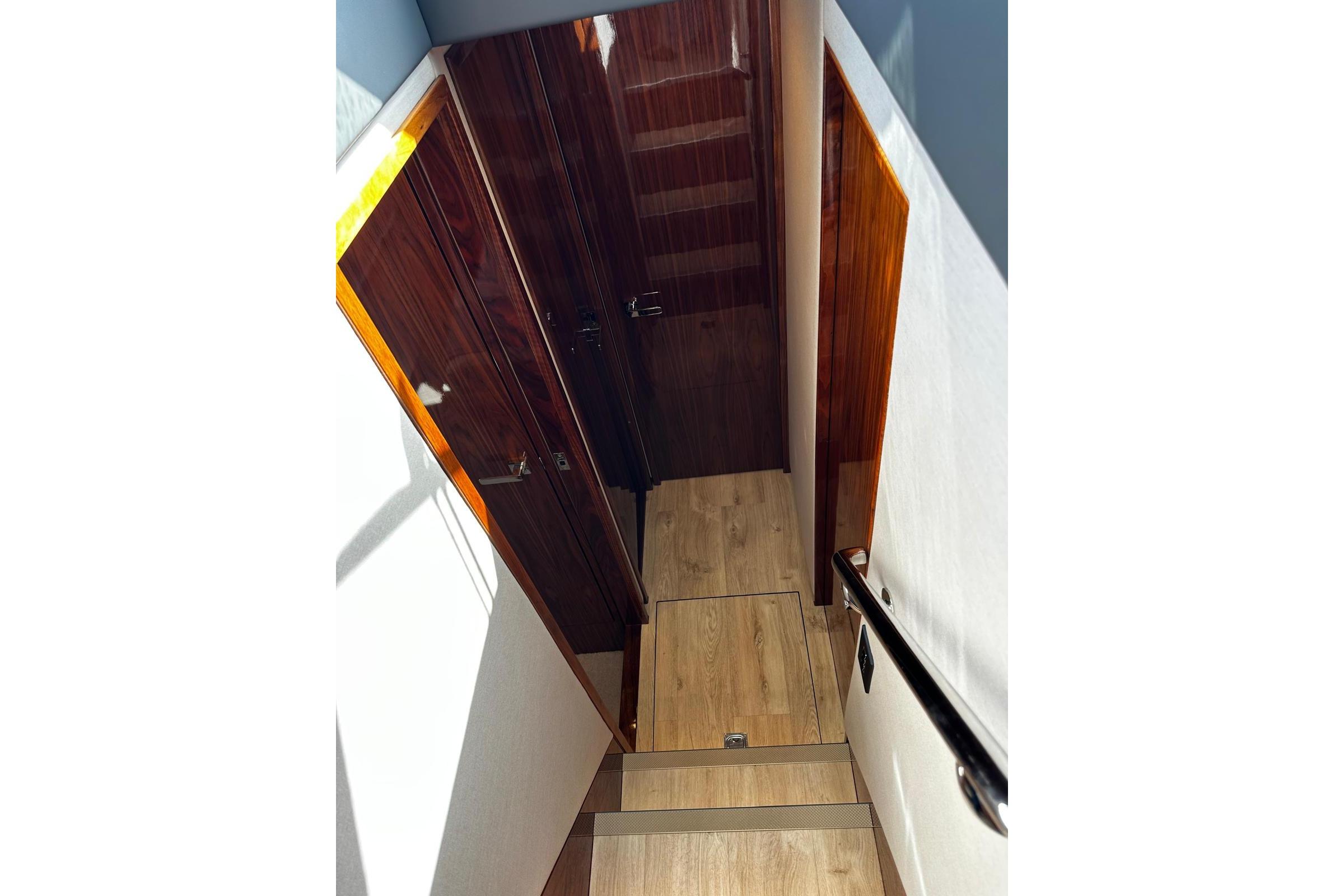 Interior staircase of 2023 Riviera 465 SUV yacht with wooden finishes.