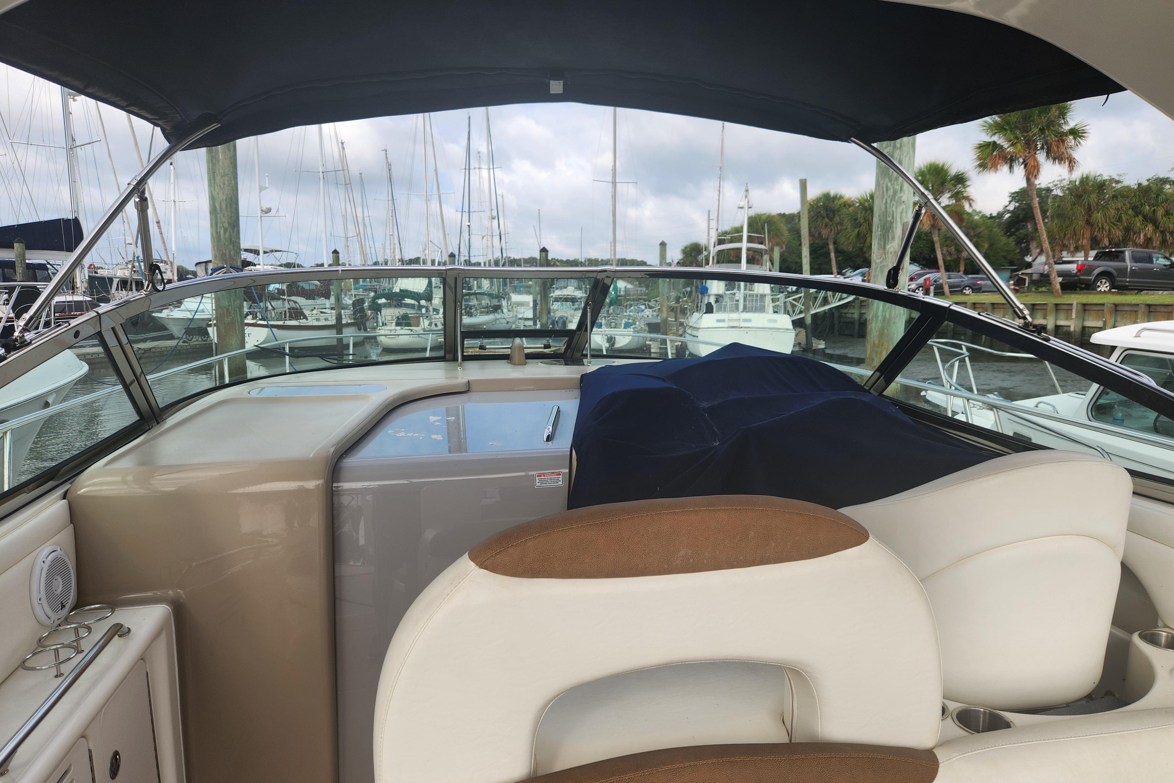 2003 Sea Ray 360 Sundancer yacht interior with marina view, featuring seating and helm area.