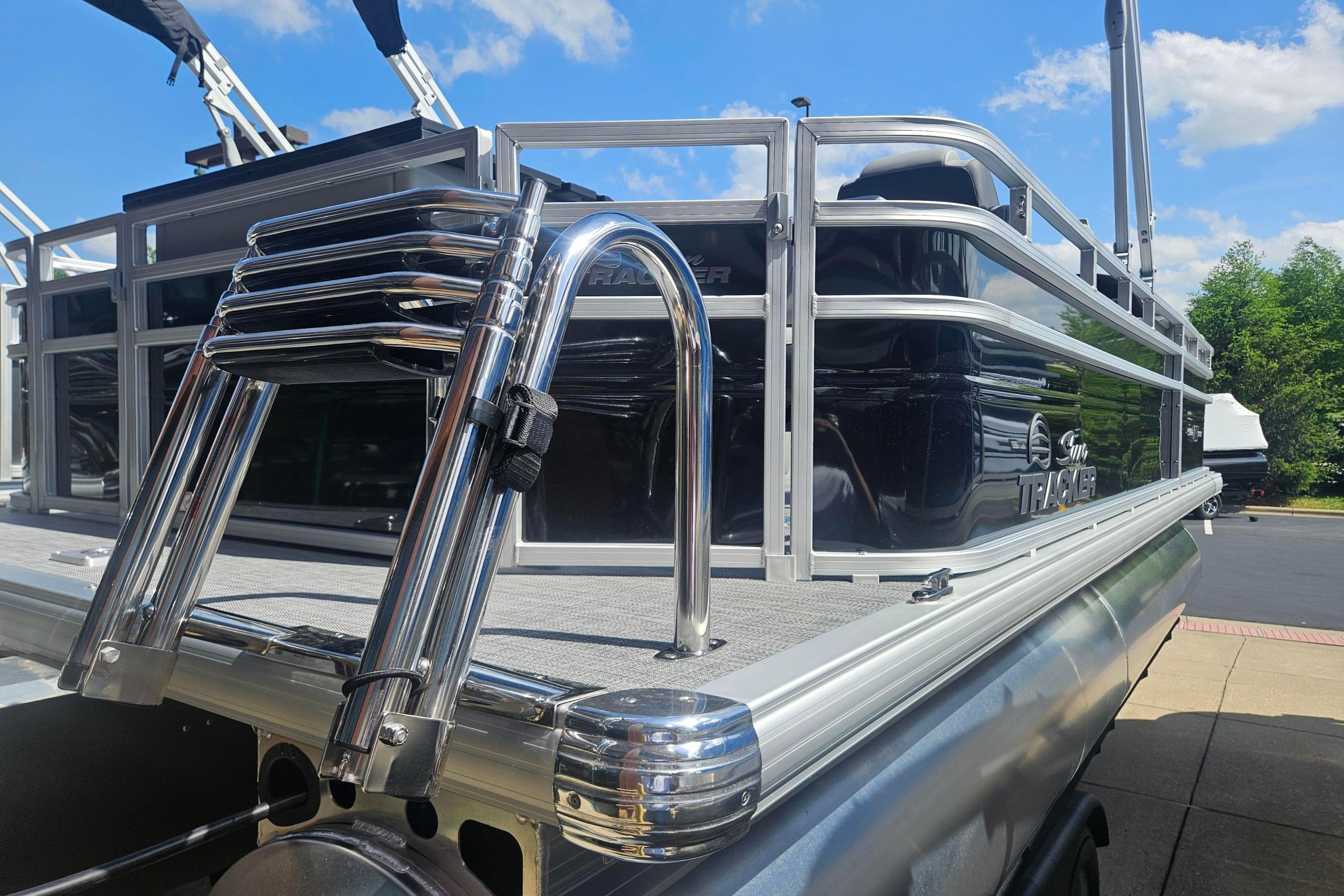 2026 Sun Tracker SportFish 20 DLX pontoon boat with chrome ladder, docked under blue sky.