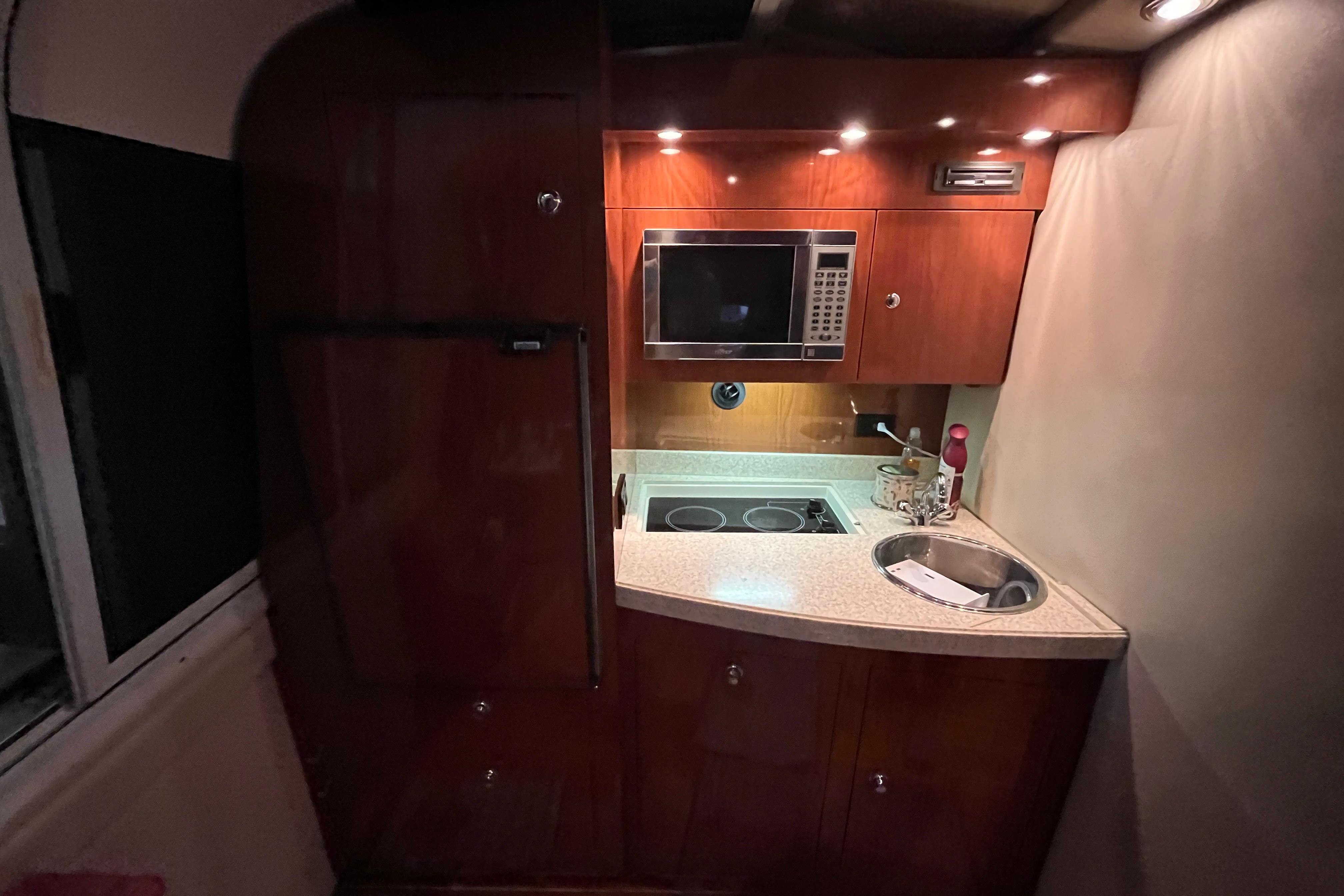 2007 Regal 3760 IB Commodore yacht kitchen with microwave, stove, and sink.
