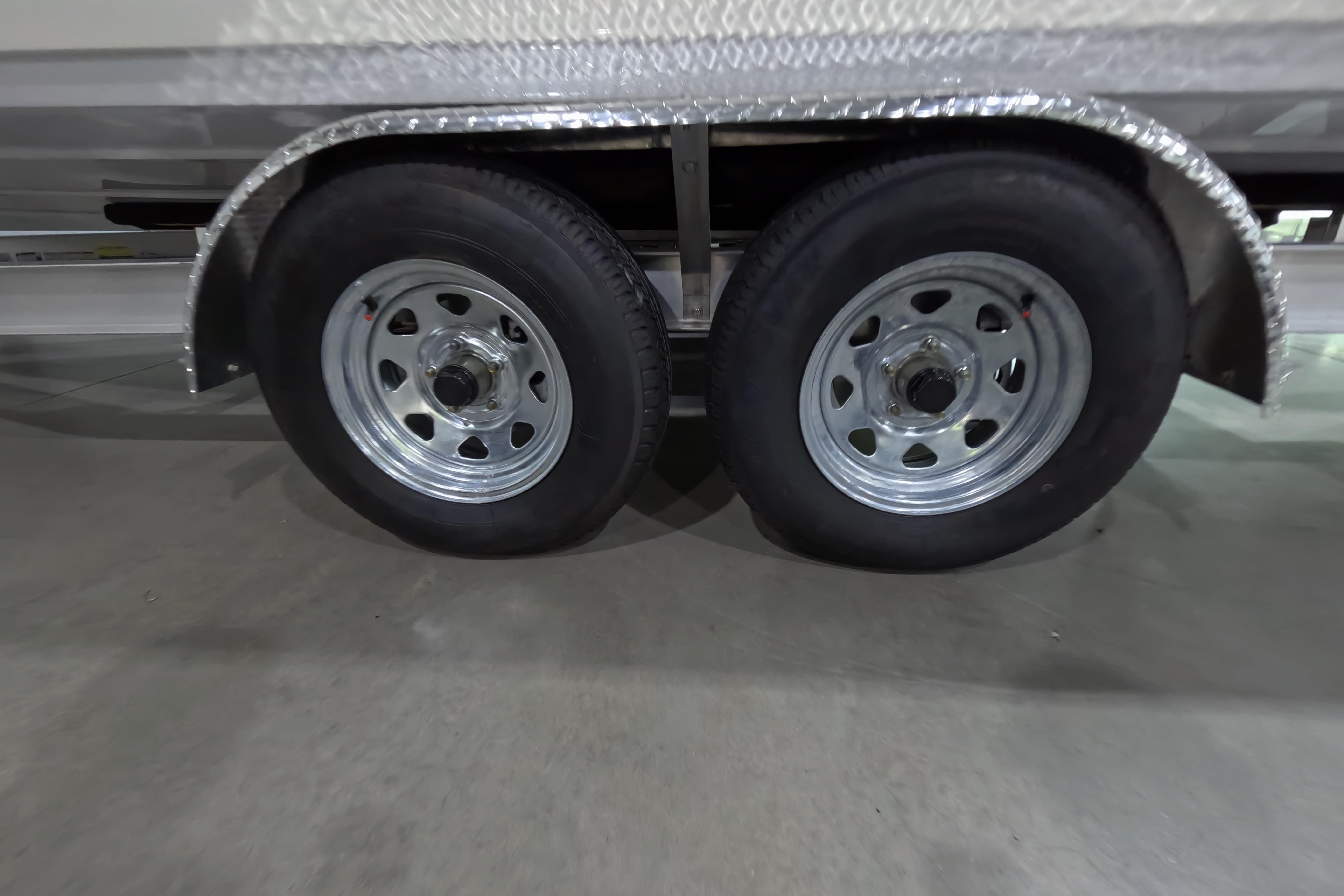 Dual wheels of a 2026 Skeeter SX221 boat trailer on concrete floor.
