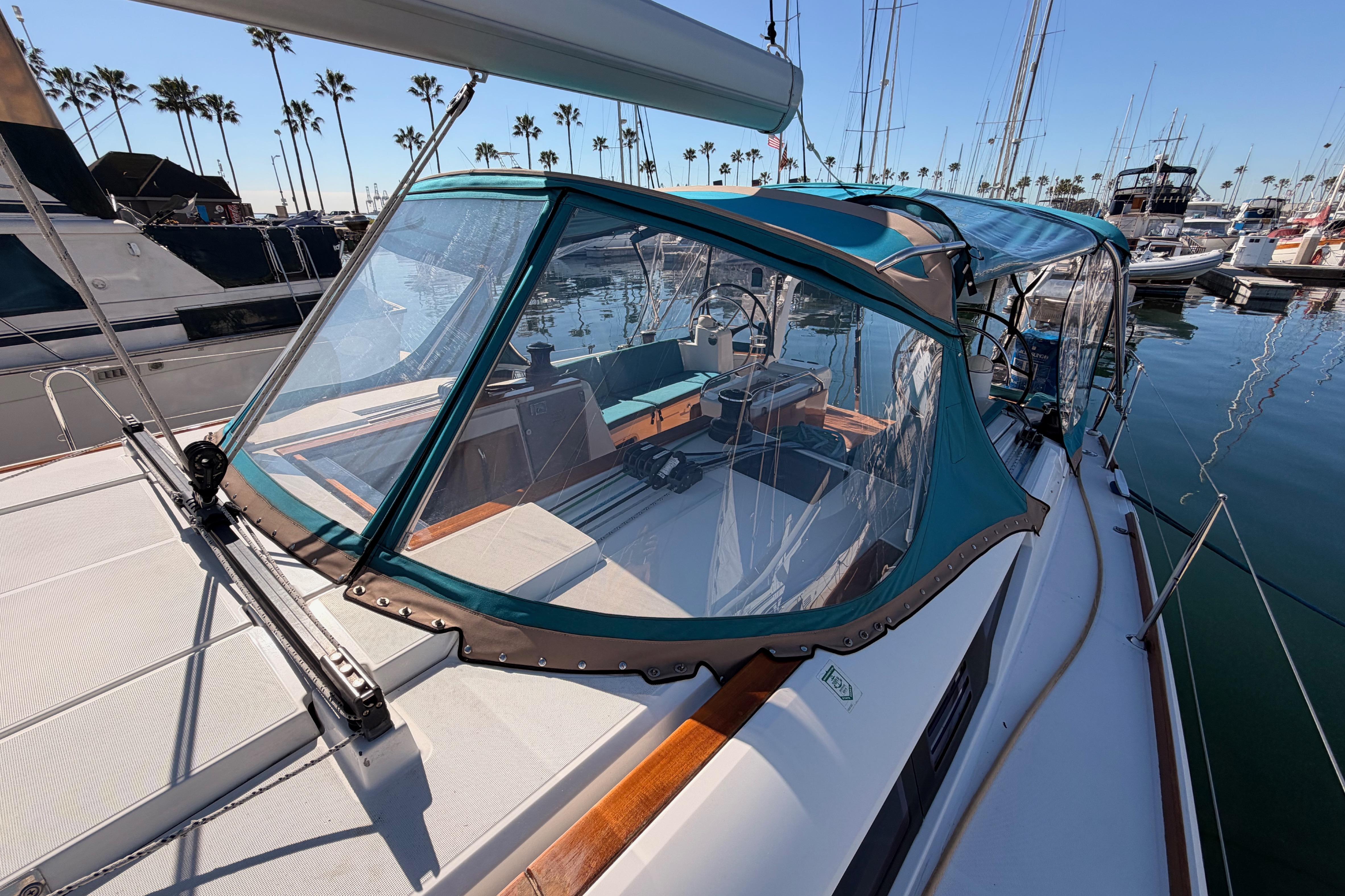 2014 Jeanneau Sun Odyssey 469 sailboat with blue canopy docked in marina.