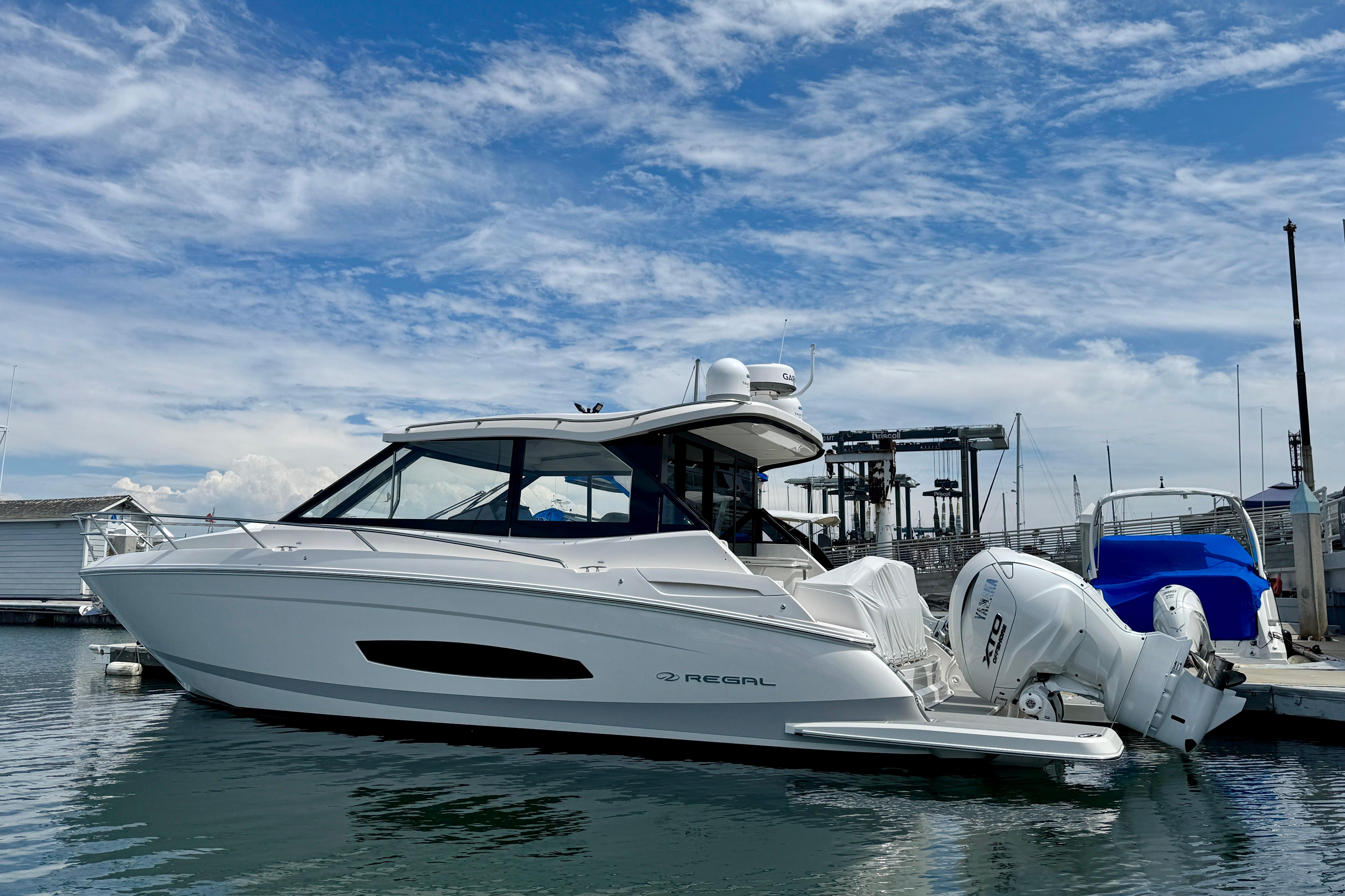2026 Regal 36 XO boat docked at marina under blue sky.