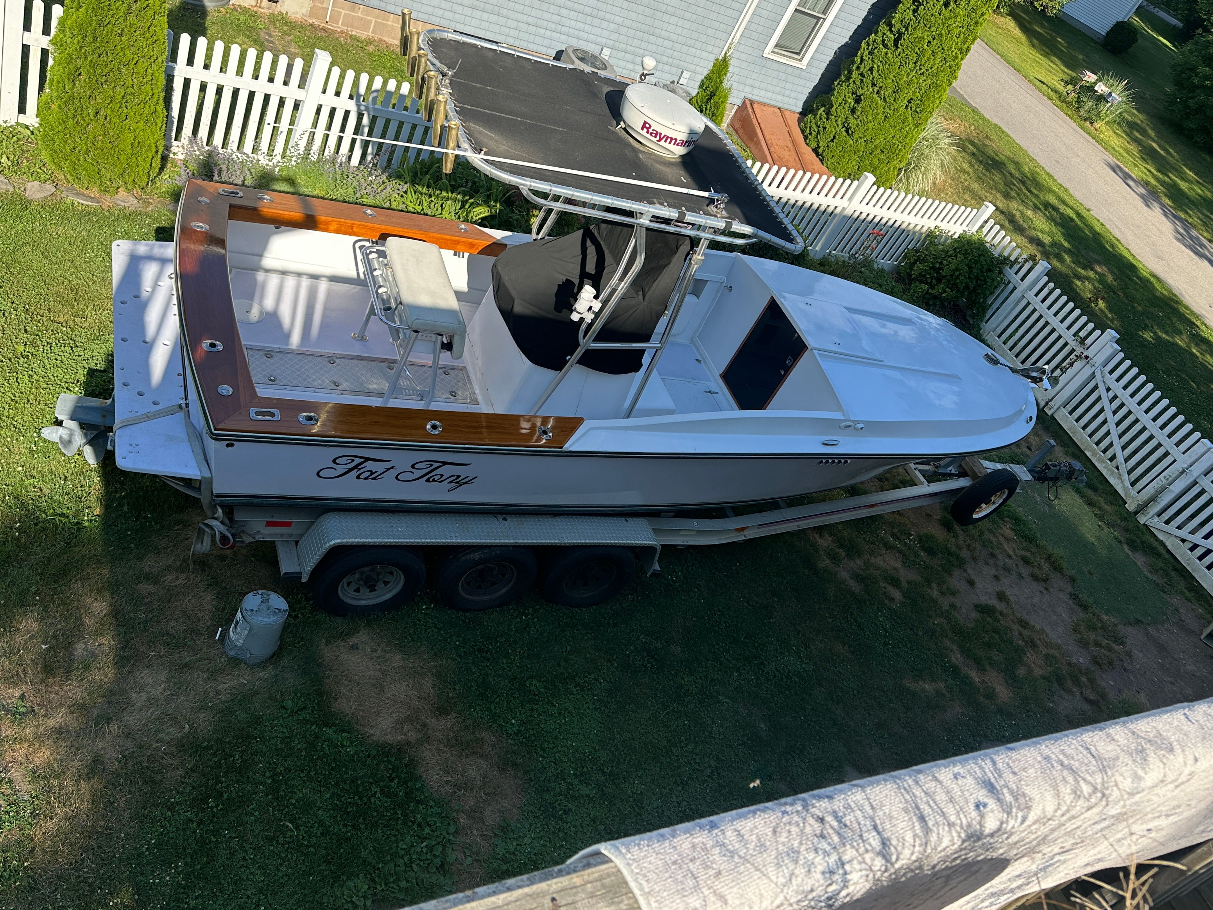 A 1976 Blackfin Fisherman boat on a trailer, surrounded by a white picket fence.