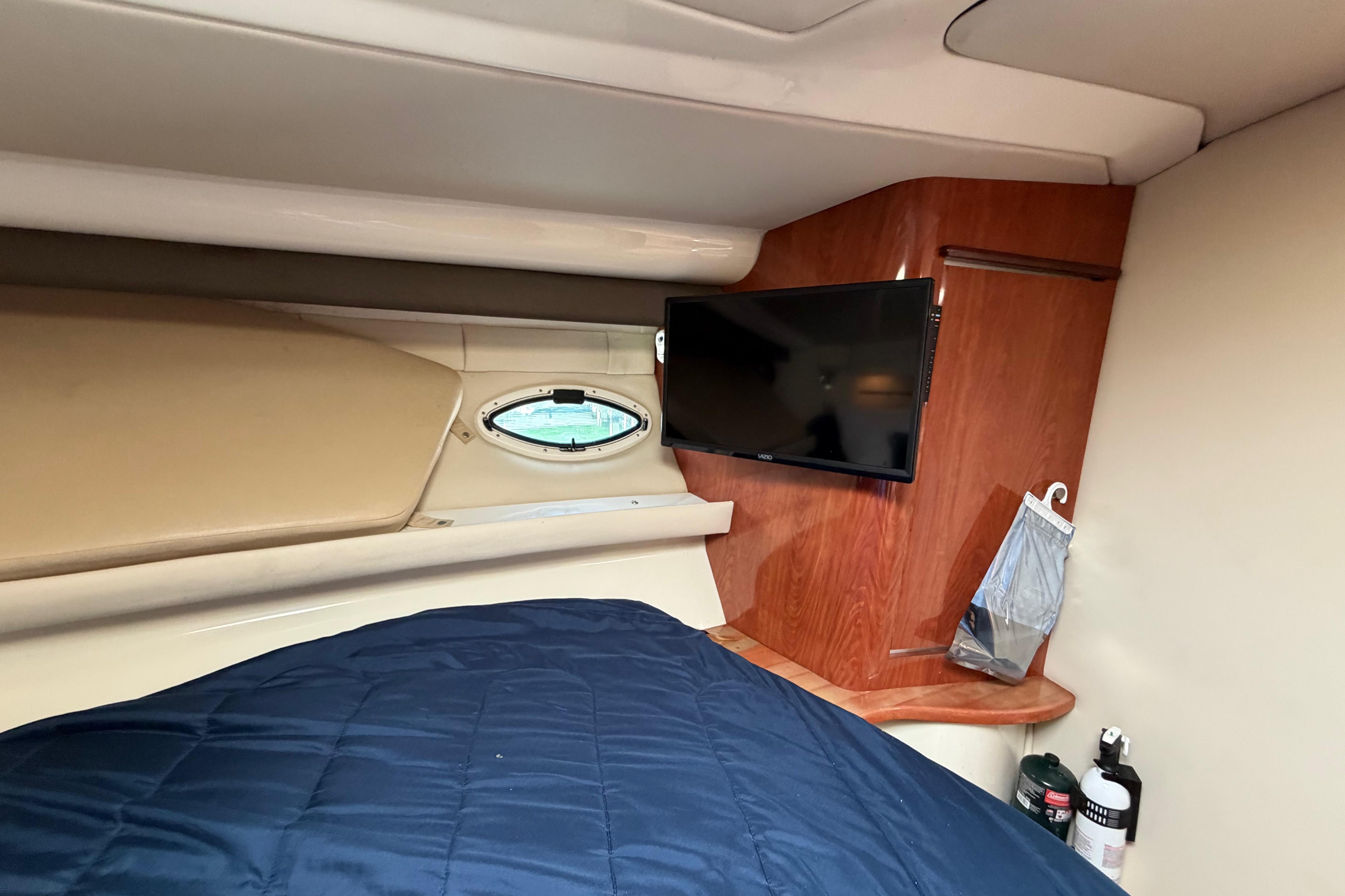 Interior of 2007 Monterey 350 Sport Yacht with TV, porthole, and blue bedding.