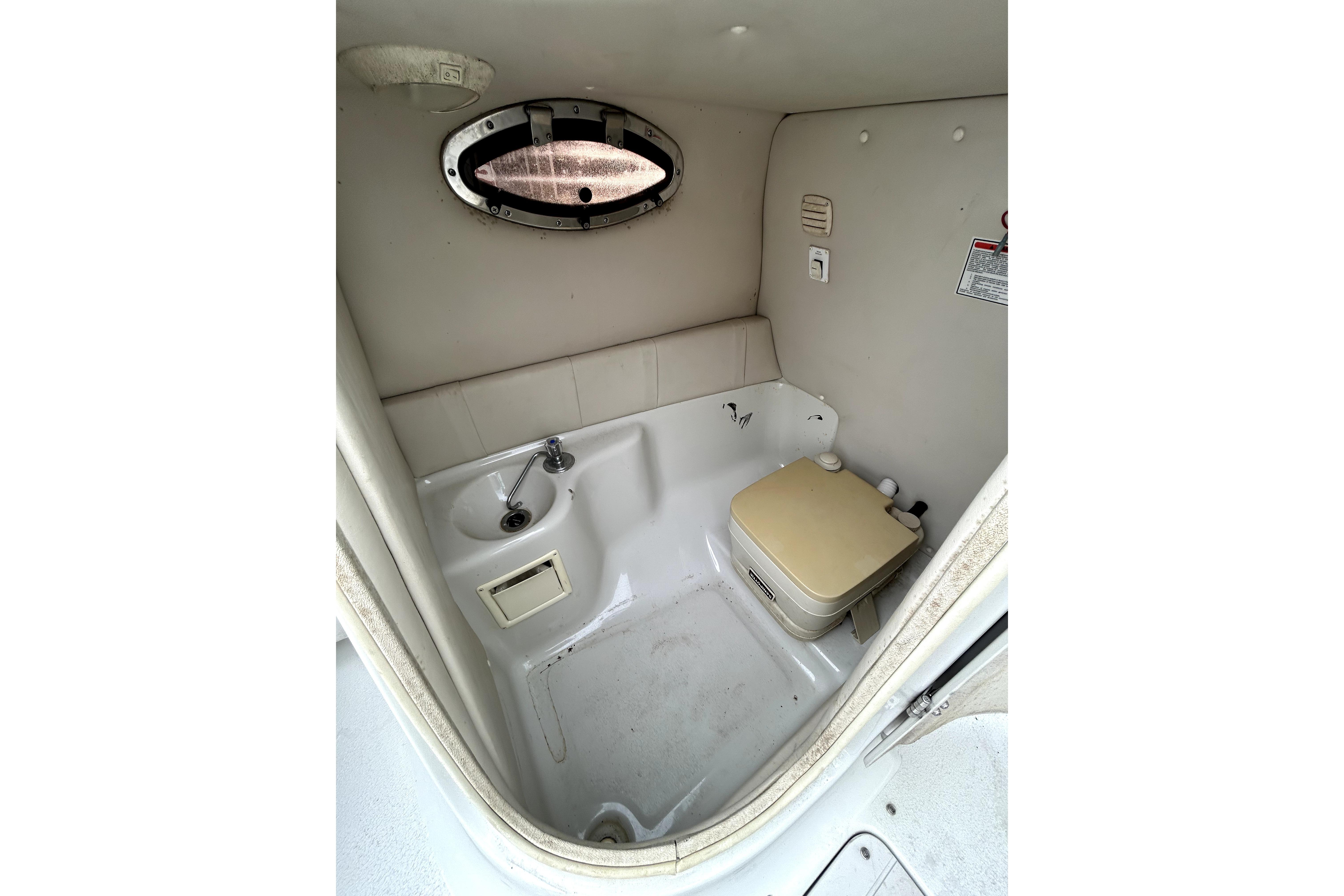 2001 Crownline 239 DB boat interior with compact bathroom and porthole window.