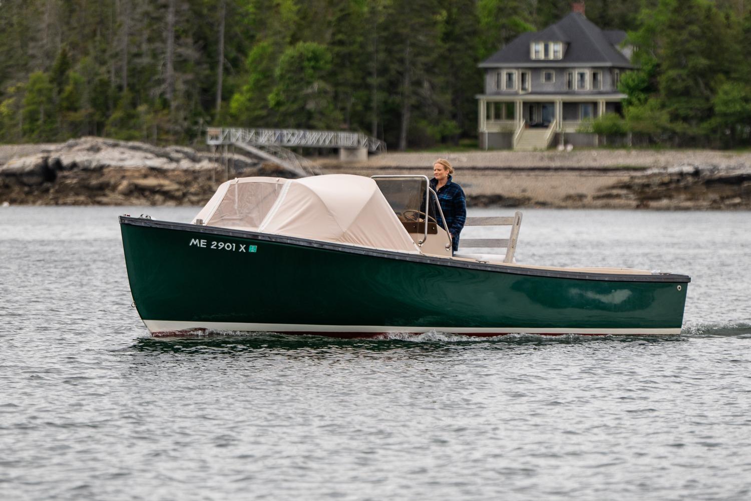 1989 Ellis 24 Open boat cruising near a shoreline with a house in the background.