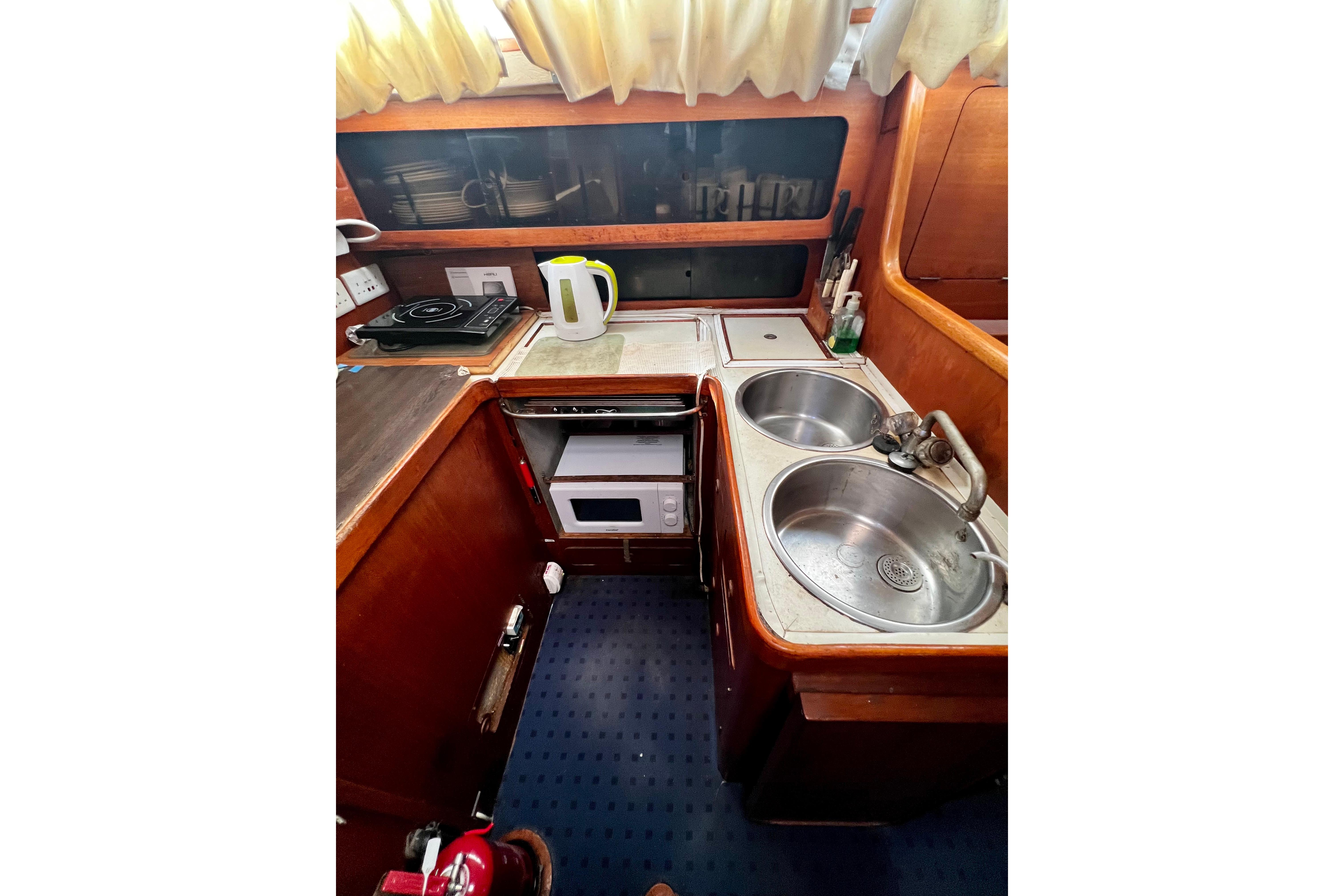Compact kitchen in a 1990 Moody 376 yacht with dual sinks and appliances.