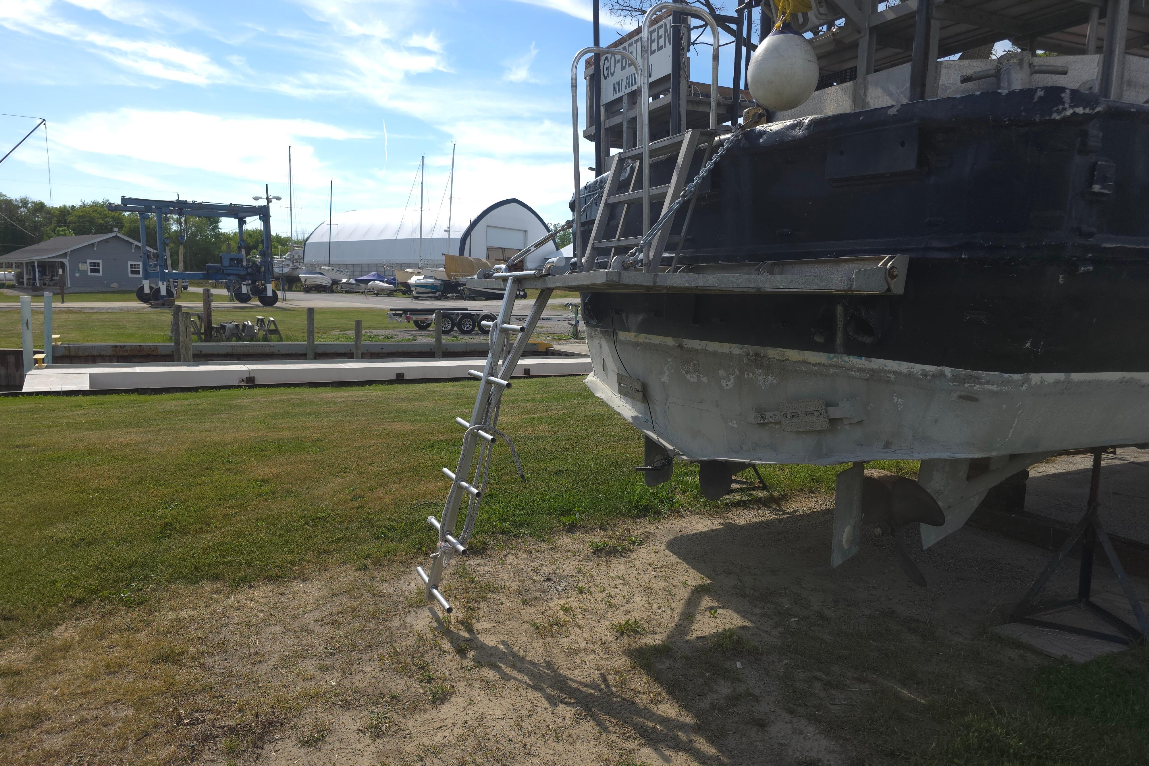 1974 Breaux's Bay Craft passenger boat on land with ladder and marina background.