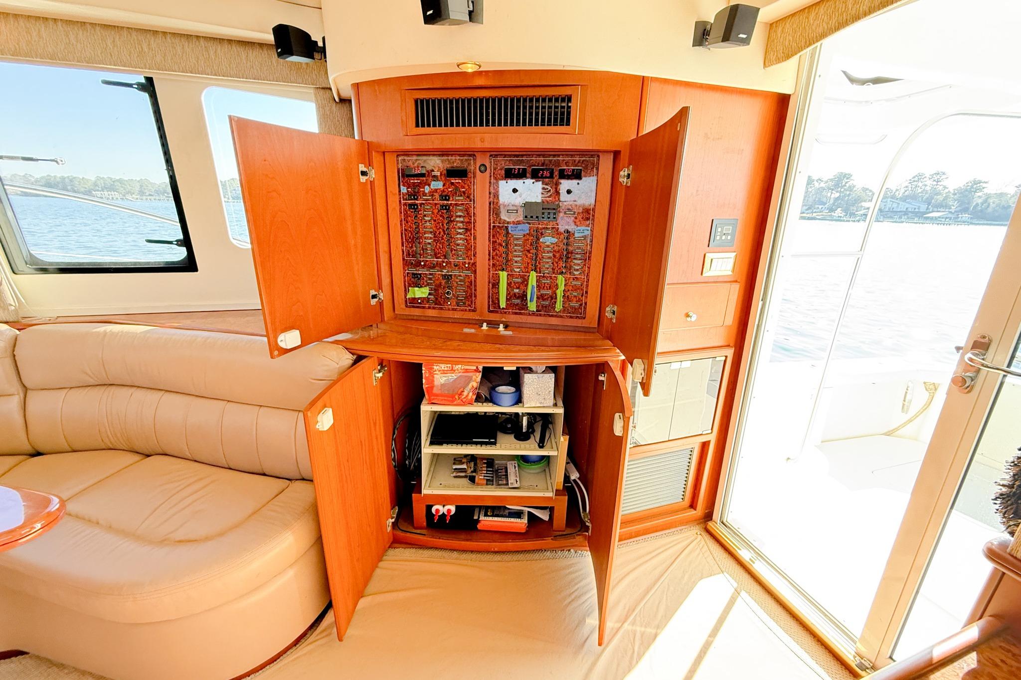 2004 Silverton 48 Convertible yacht interior with open electrical panel and beige seating.