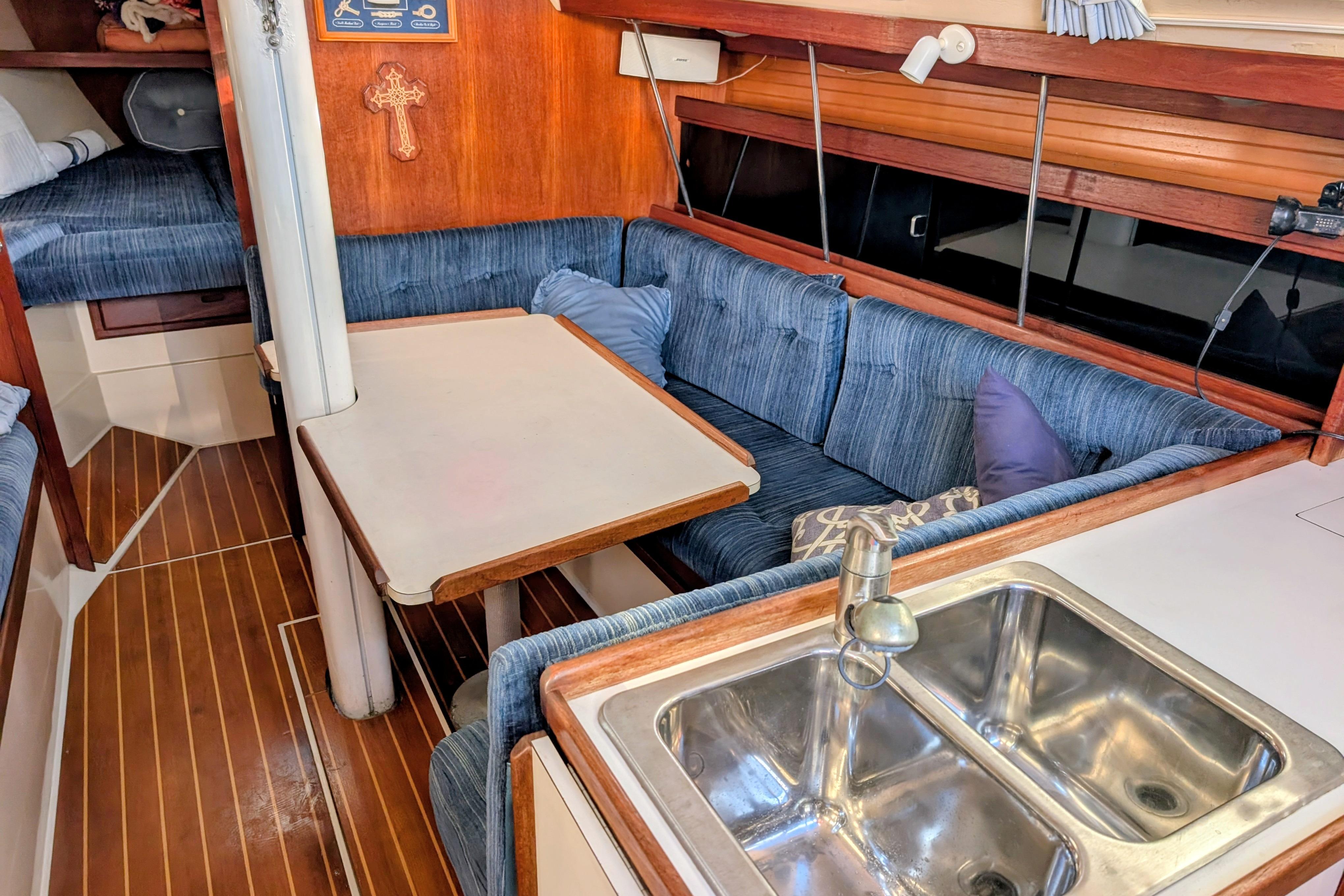 Interior of a 1989 Catalina 34 sailboat with cozy seating and a compact kitchen area.
