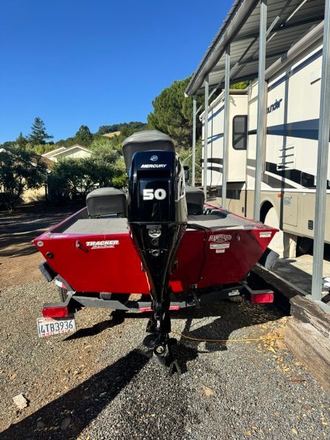 A red Bass Tracker boat with a 50 HP Mercury engine is on a trailer.