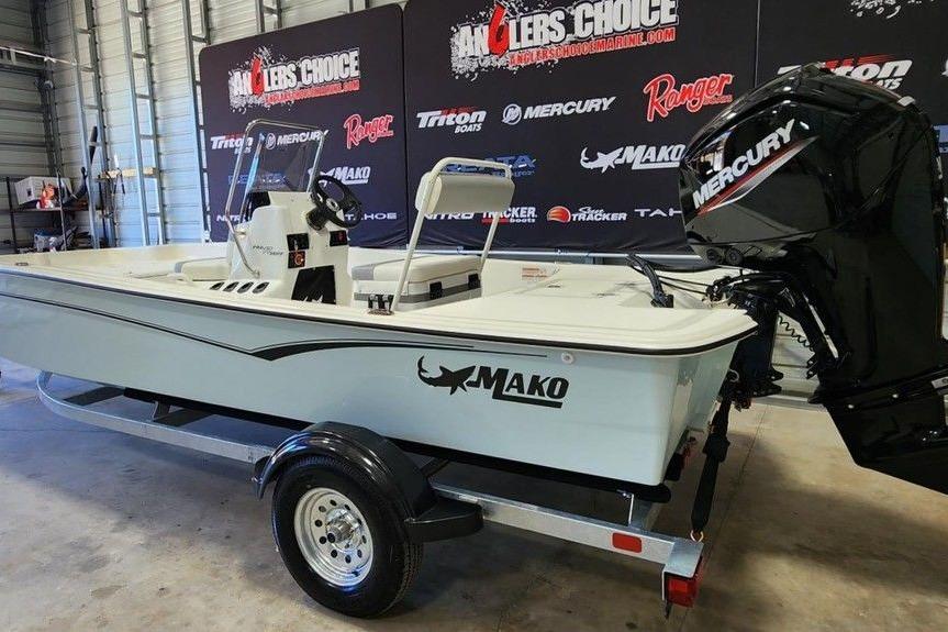 2026 Mako Pro Skiff 17 CC boat with Mercury engine on trailer in showroom.