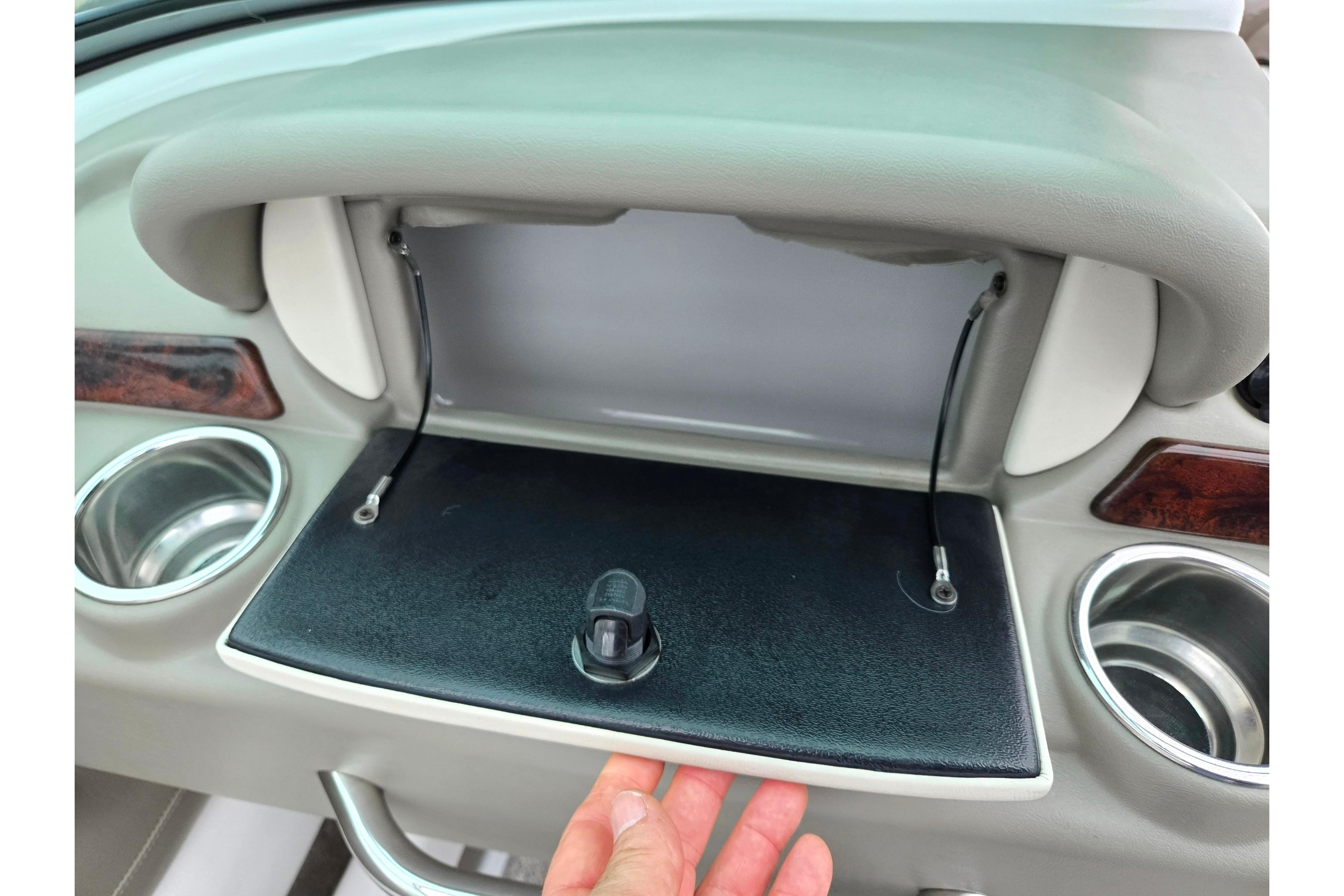 2012 Crownline 235 SS boat dashboard with open glove compartment and cup holders.