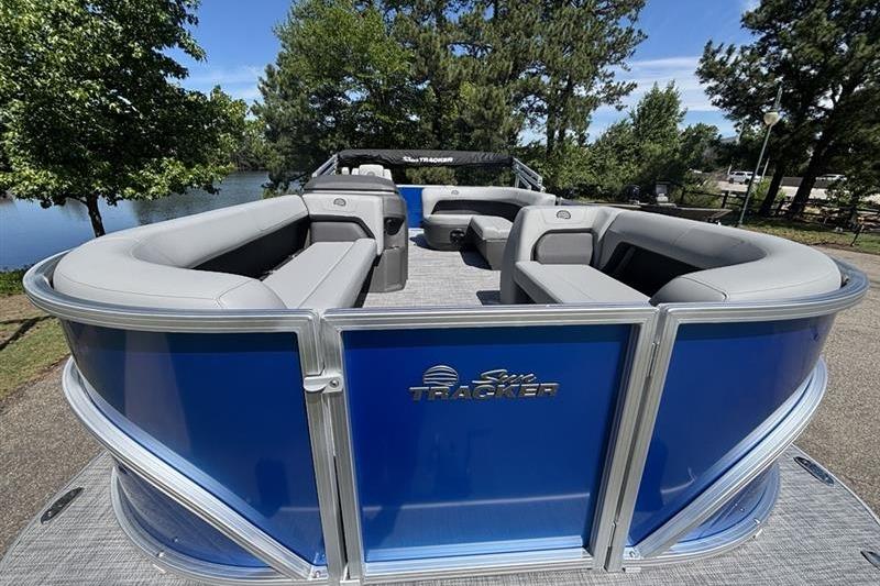 2026 Sun Tracker Party Barge 18 DLX pontoon boat with spacious seating, docked by a scenic lake.