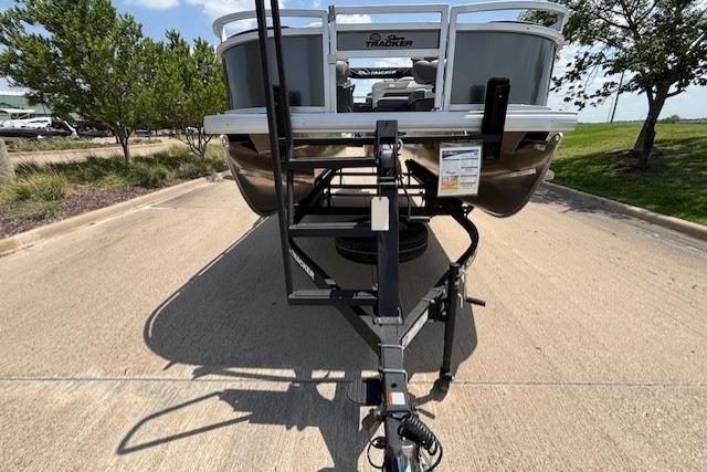 2026 Sun Tracker Bass Buggy 18 DLX pontoon boat on trailer, parked on concrete driveway.