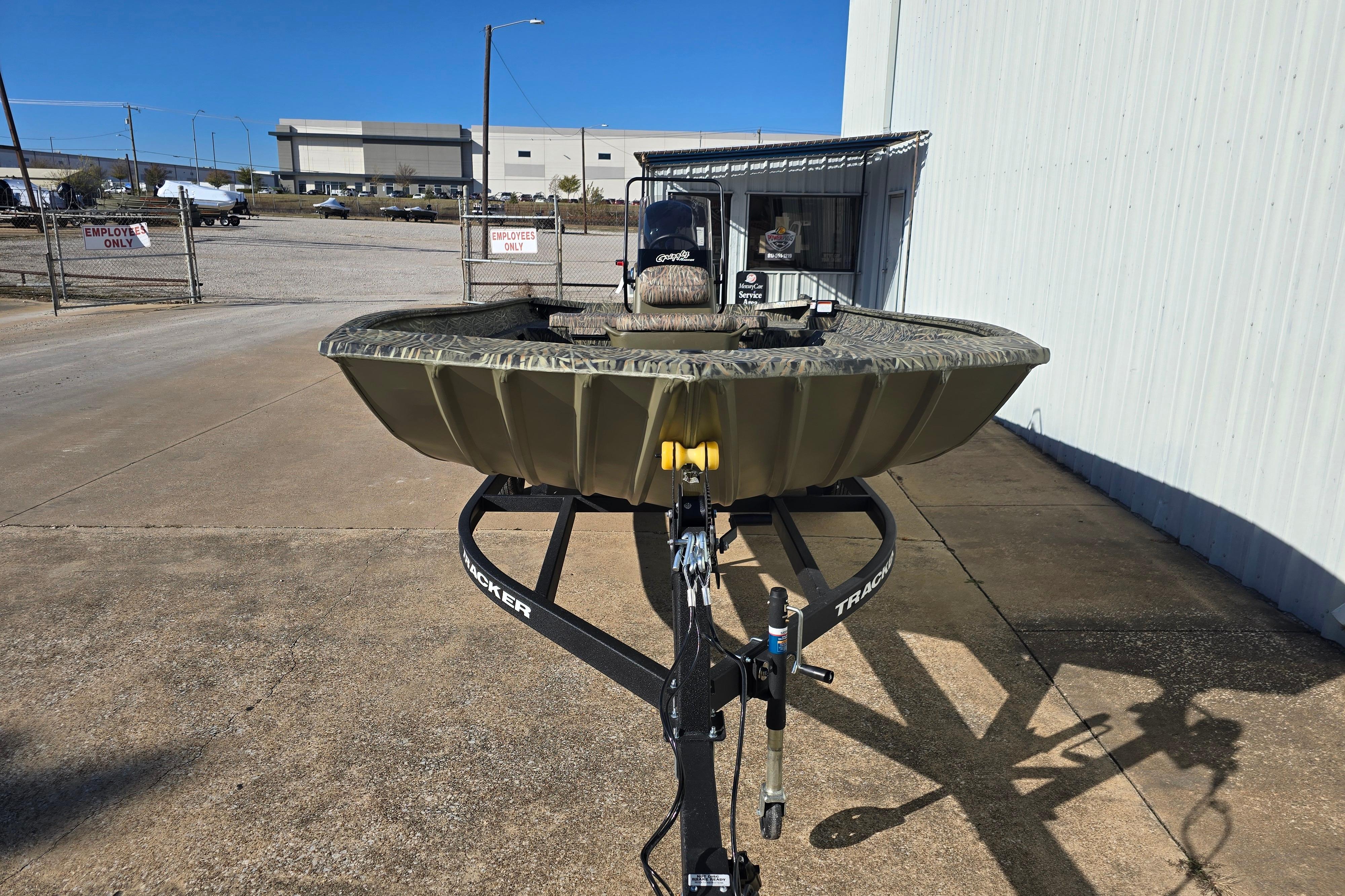 2026 Tracker Grizzly 2072 CC boat on trailer, parked outdoors near industrial buildings.