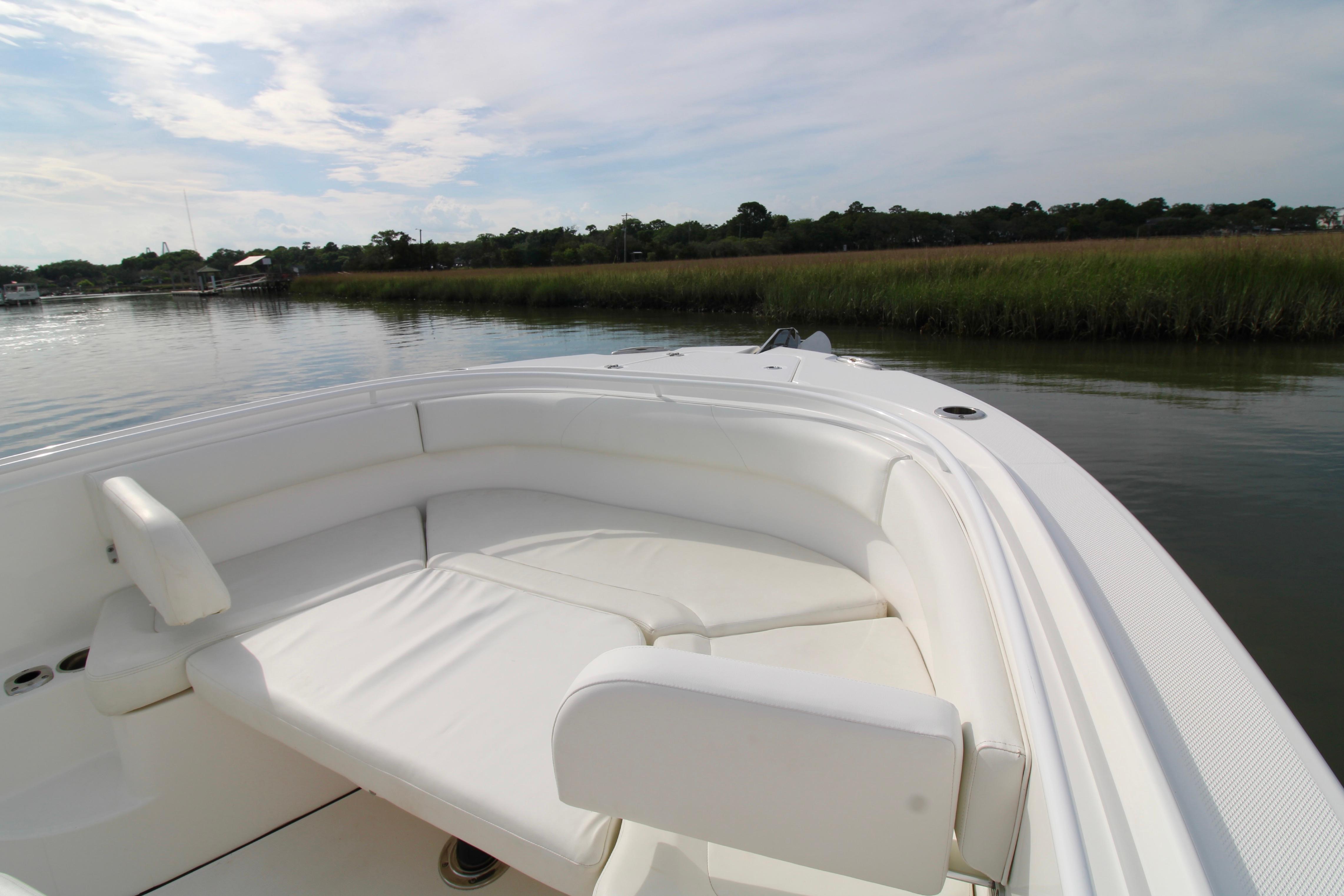 2022 Edgewater 280CC boat with white seating, docked near lush greenery and calm waters.