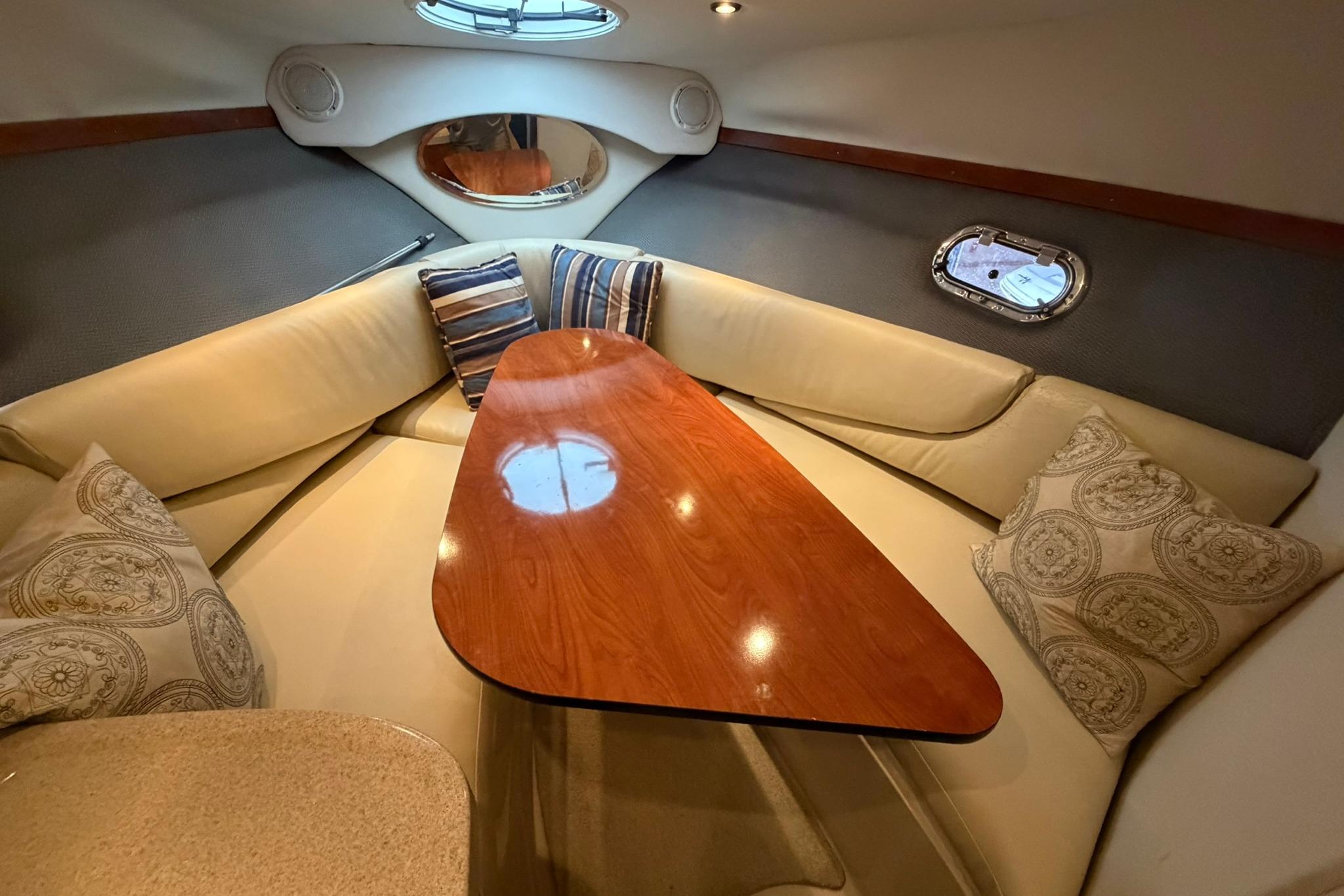 Interior of 2008 Four Winns V248 boat with cozy seating and wooden table.