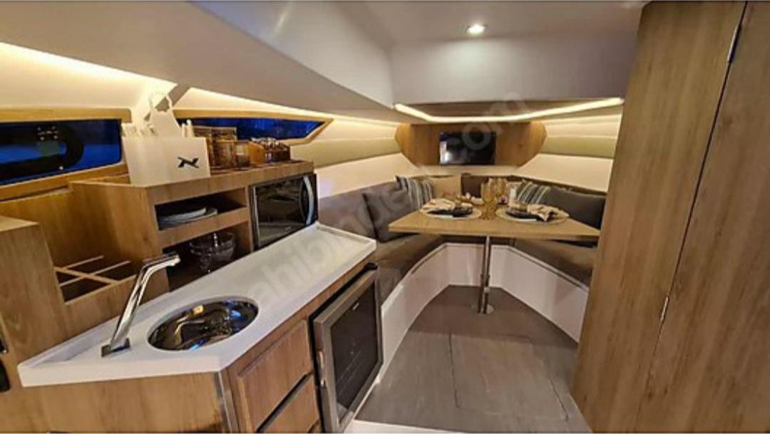 Interior of 2021 NX Boats 340 Sport Coupe, featuring a modern kitchen and cozy dining area.