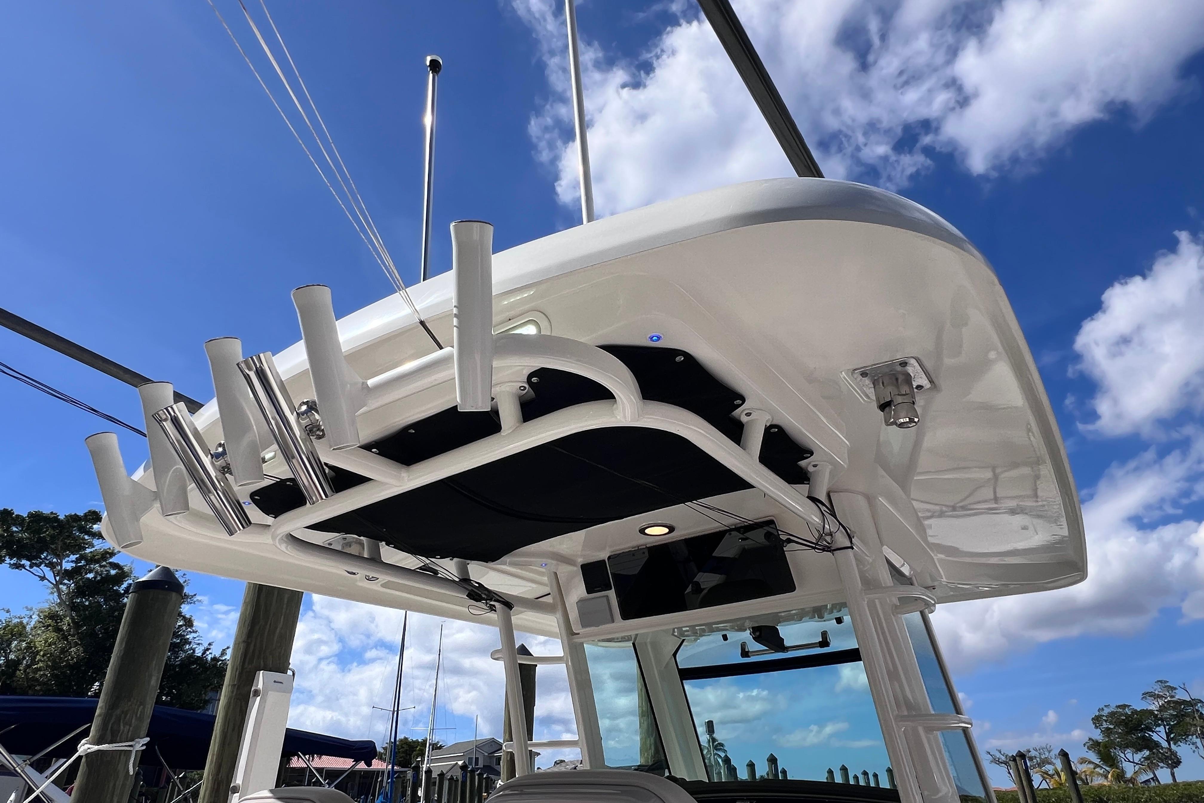 2021 Boston Whaler 330 Outrage boat, featuring a sleek overhead structure against a blue sky.