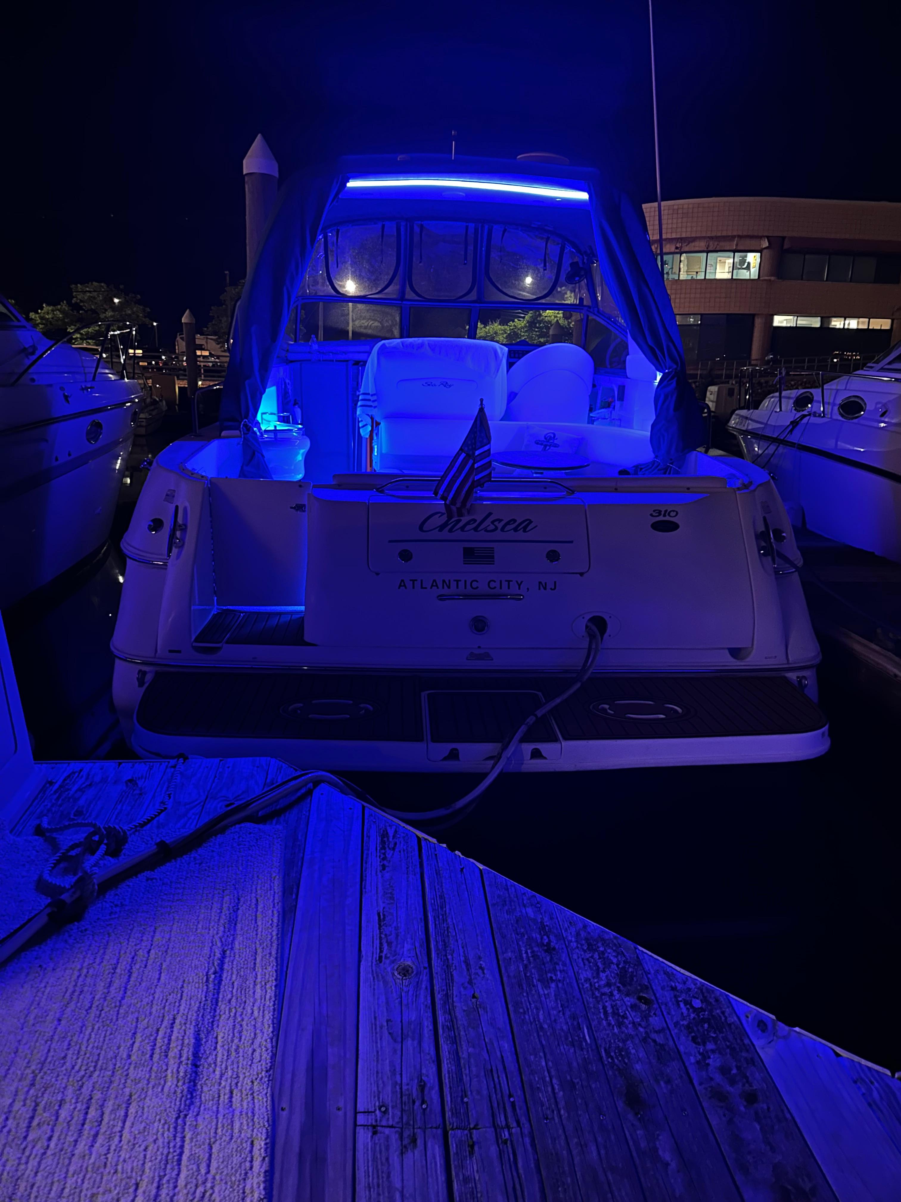 Sea Ray 310 Sundancer 2002 yacht illuminated with blue lights at night.