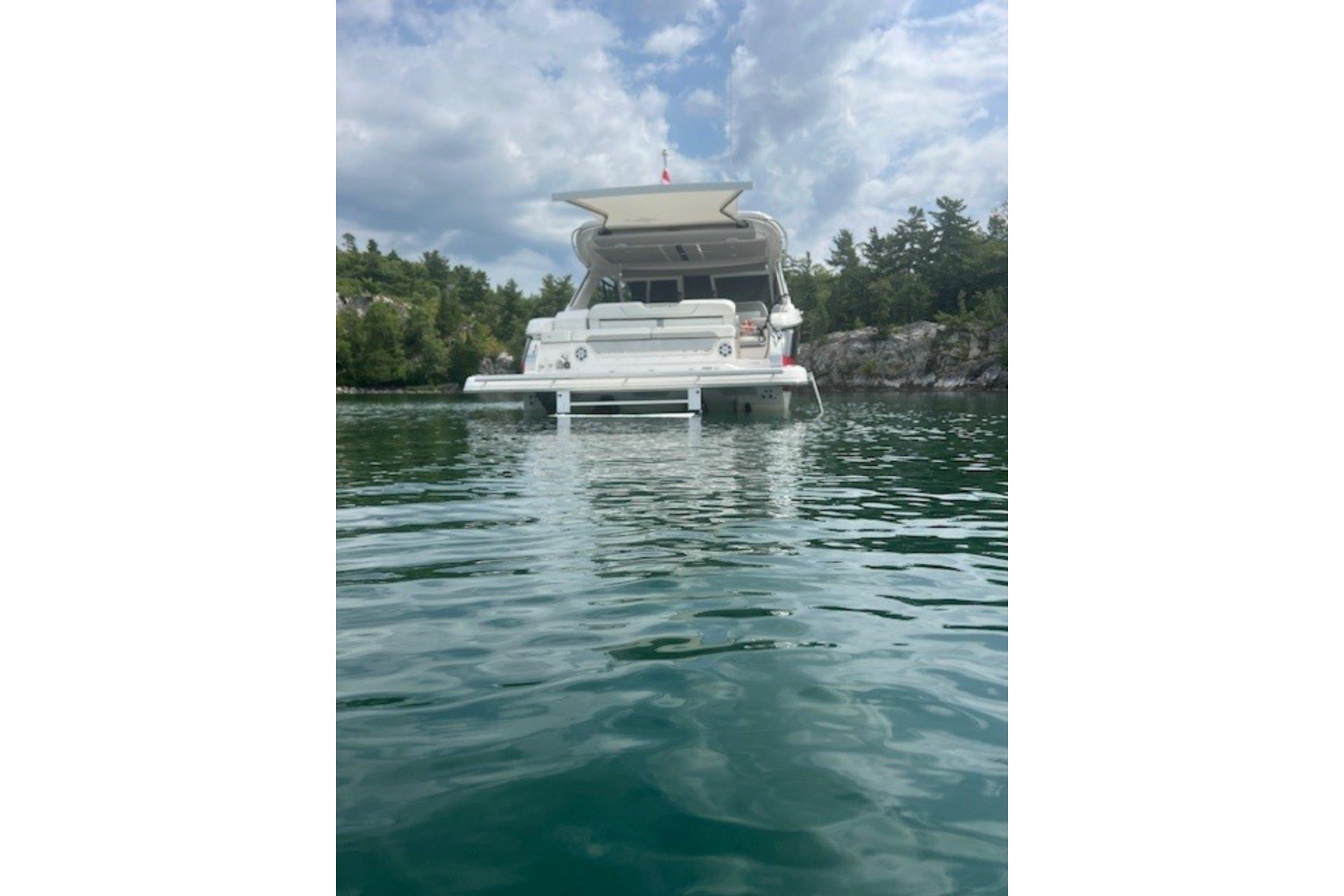 2023 Regal LS36 boat on calm water, surrounded by lush greenery and rocky shoreline.