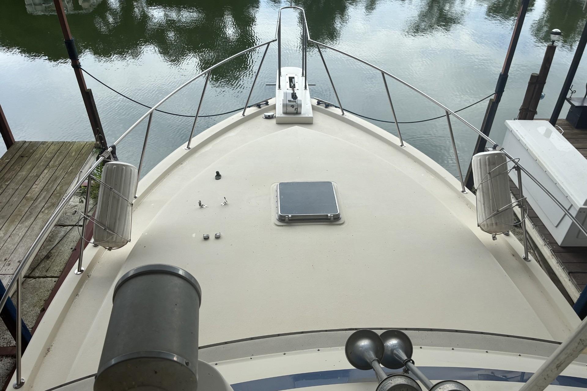 1980 Chris-Craft 360 Commander boat deck with railing, docked by calm water.