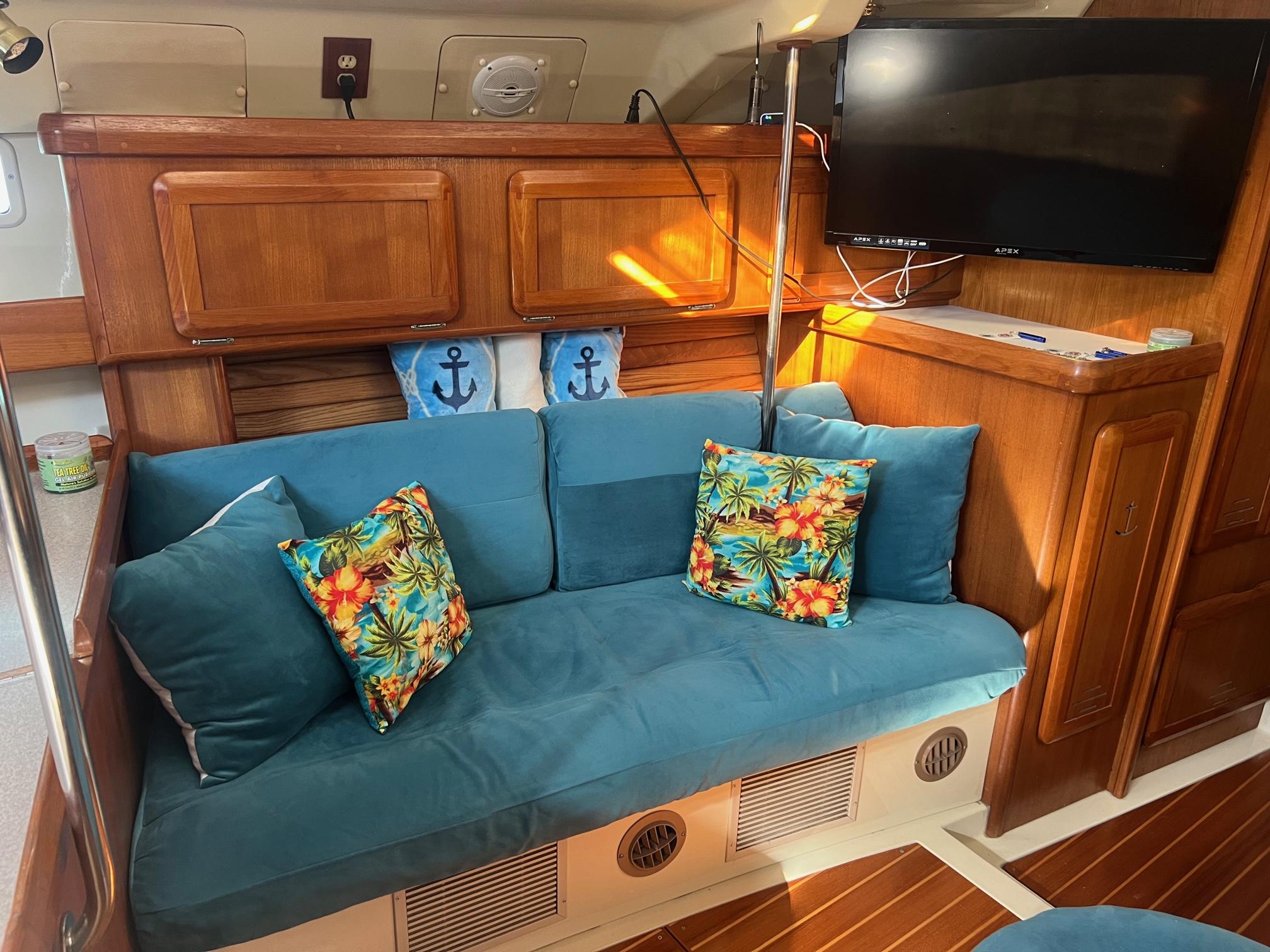 Cozy interior of 1992 Hunter 43 sailboat with blue cushions and tropical pillows.
