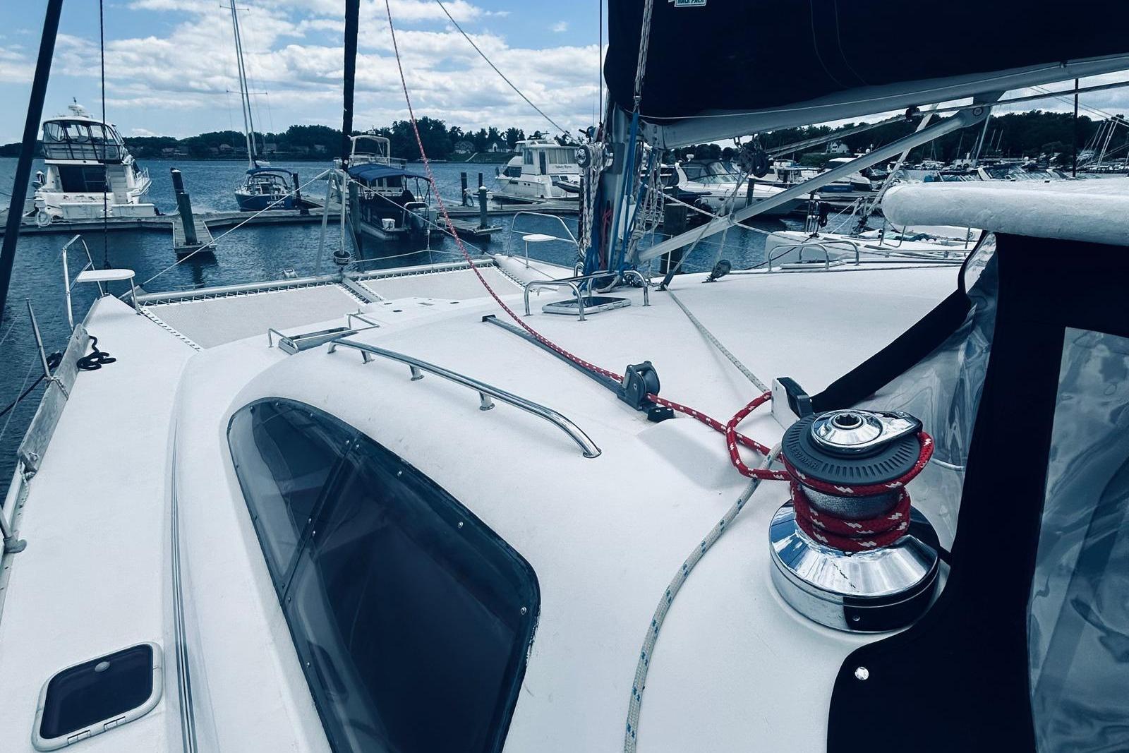 2001 Robertson & Caine Leopard catamaran docked at marina, featuring deck and winch.