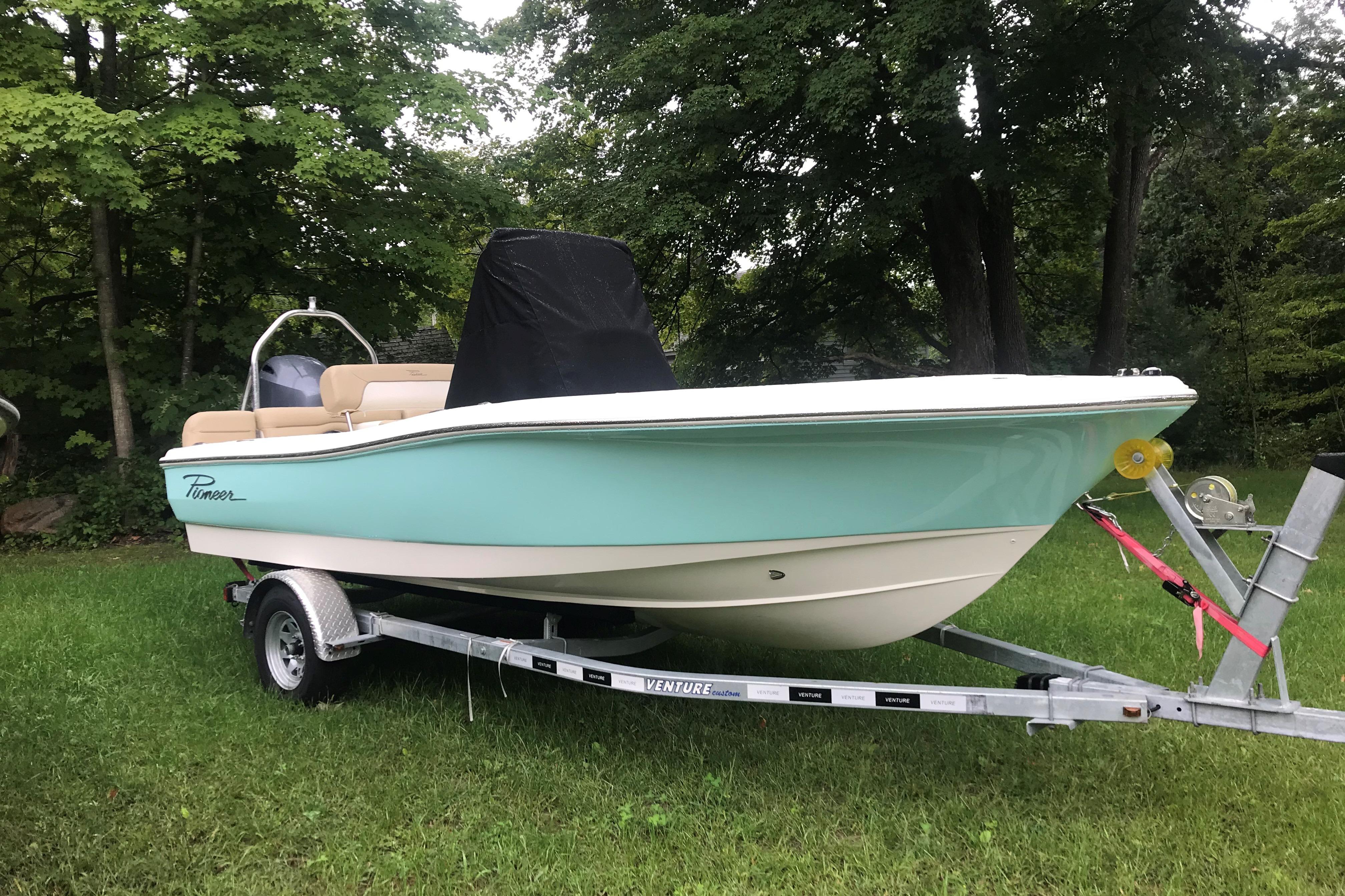 2026 Pioneer 180 Islander boat on trailer, parked on grass with trees in background.