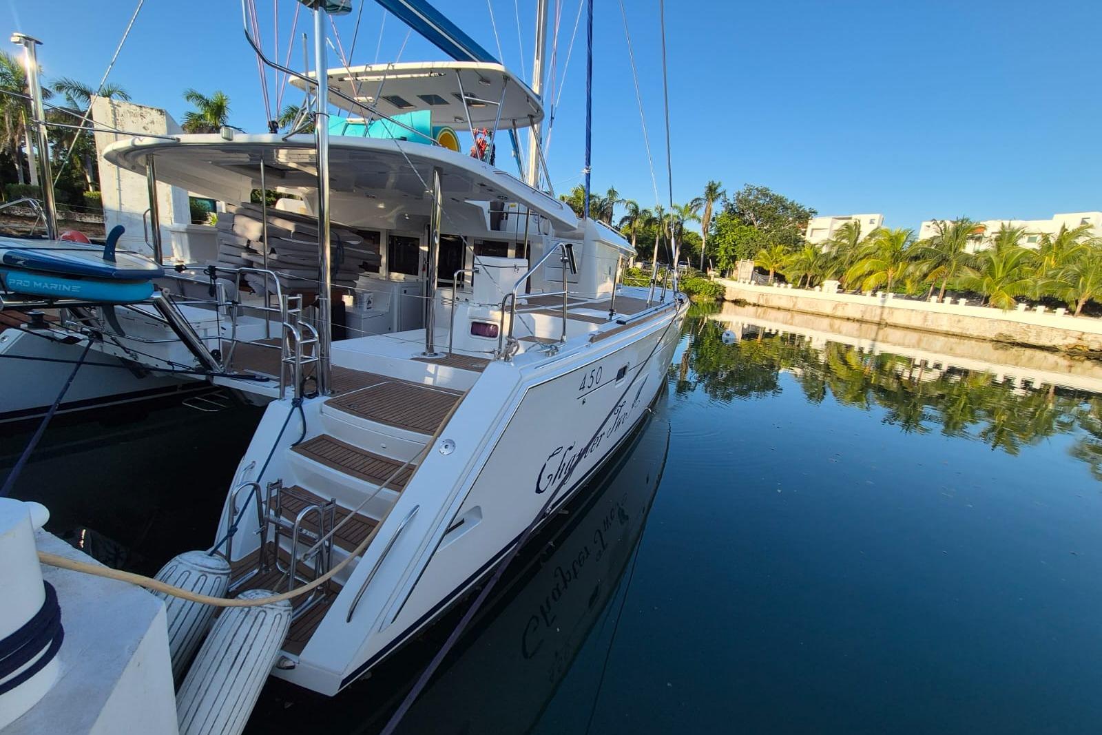 2014 Lagoon 450 catamaran docked in a serene marina with clear blue skies.